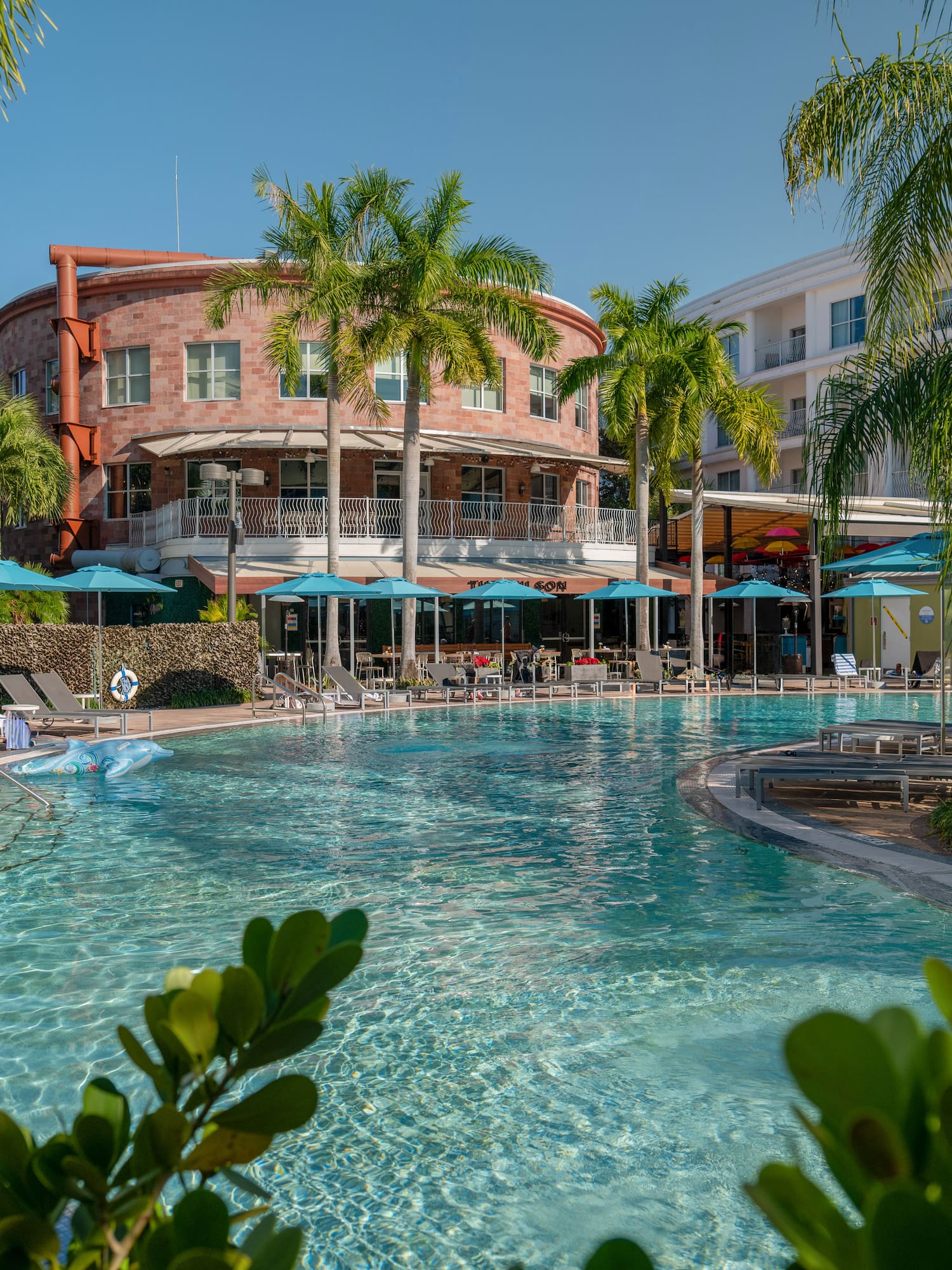 a pool with palm trees and a building