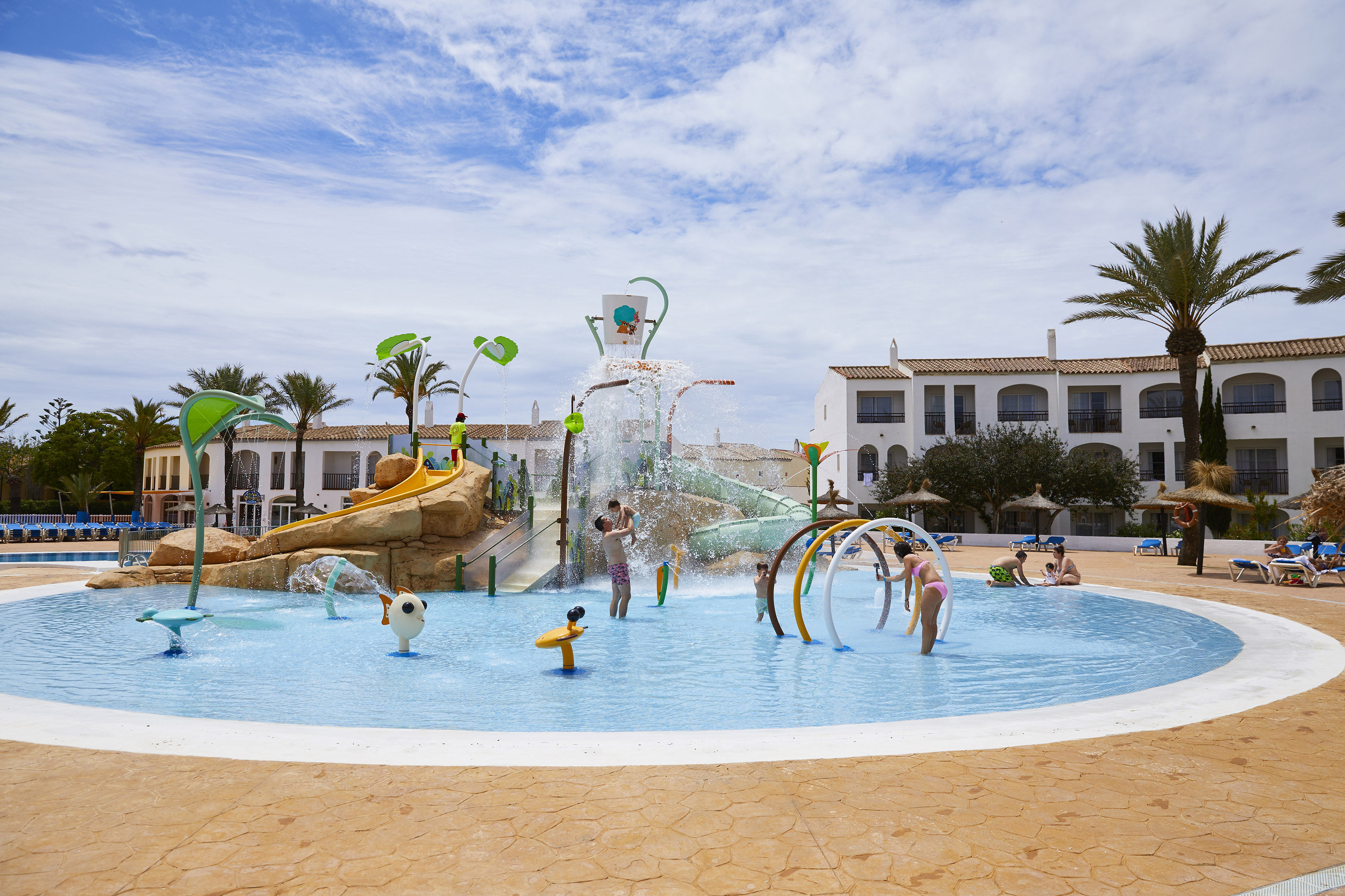 Kids splash park at resort with slides, water features, and children playing.