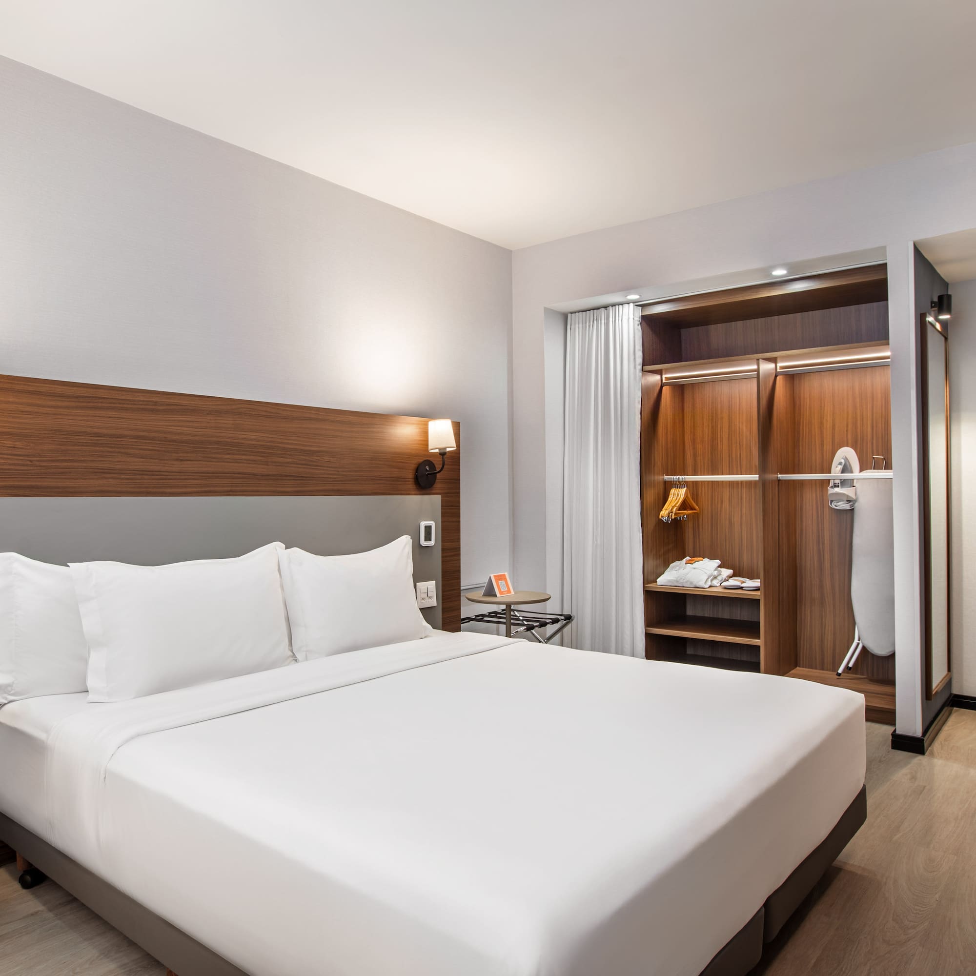 Spacious modern hotel room with king bed, wardrobe, and bathroom view.