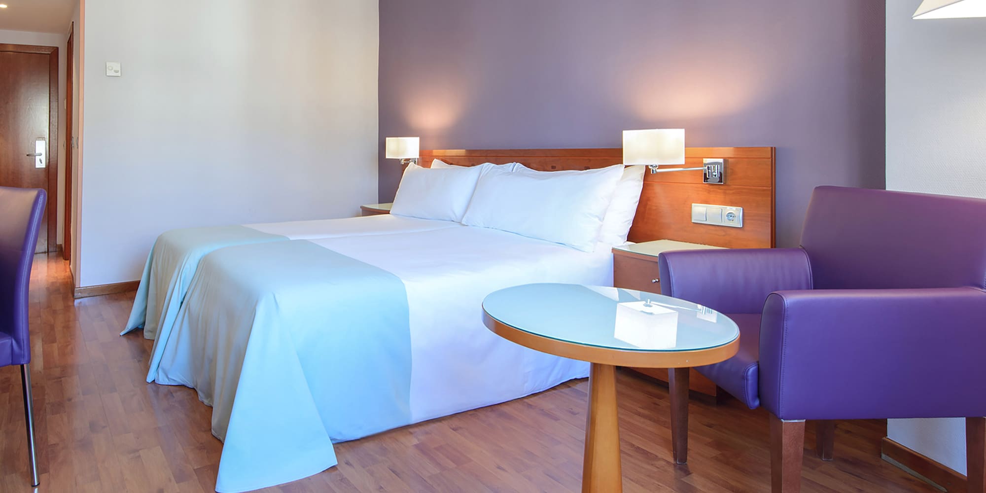 a room with a bed and purple chairs