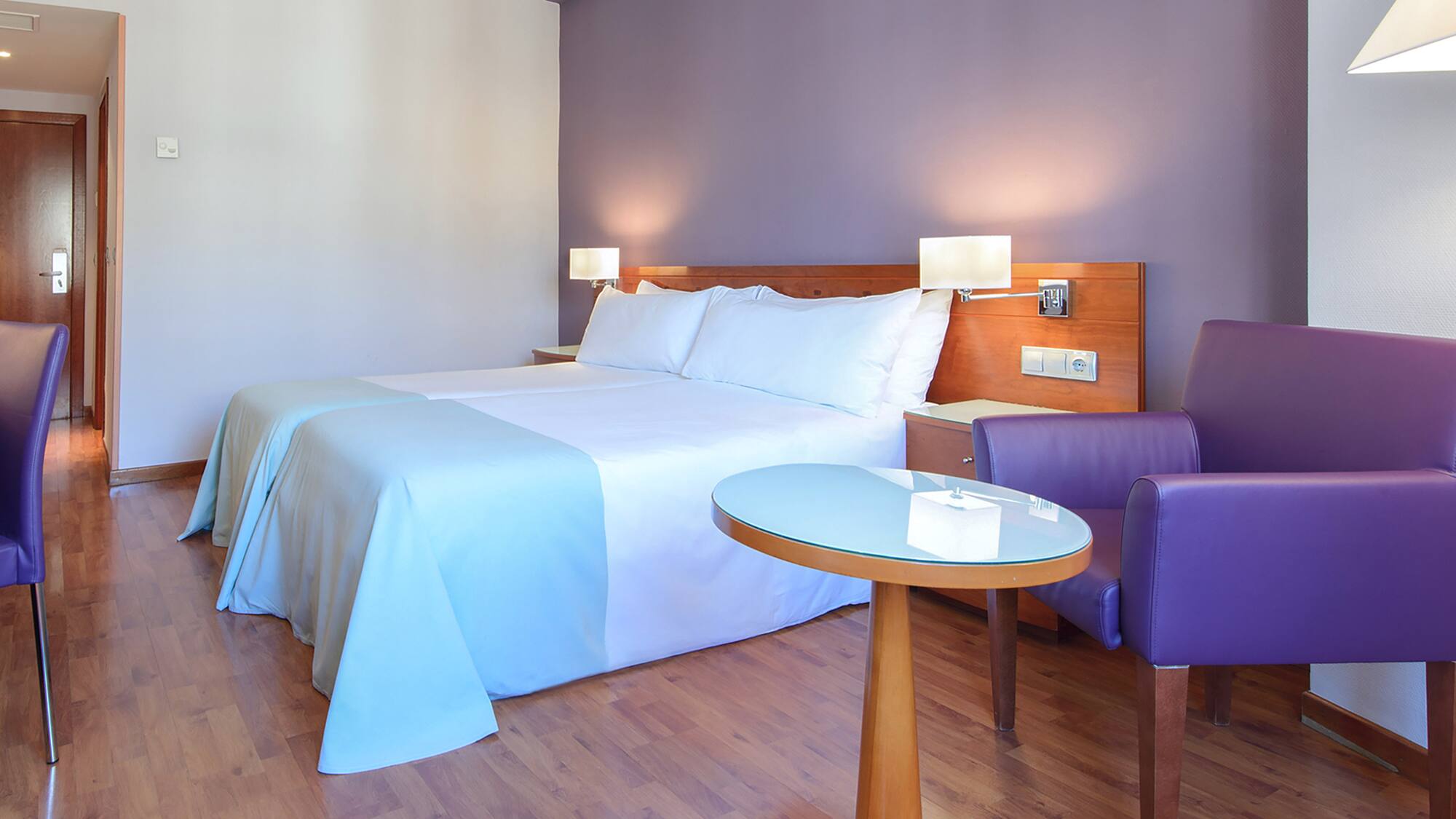 a room with a bed and purple chairs