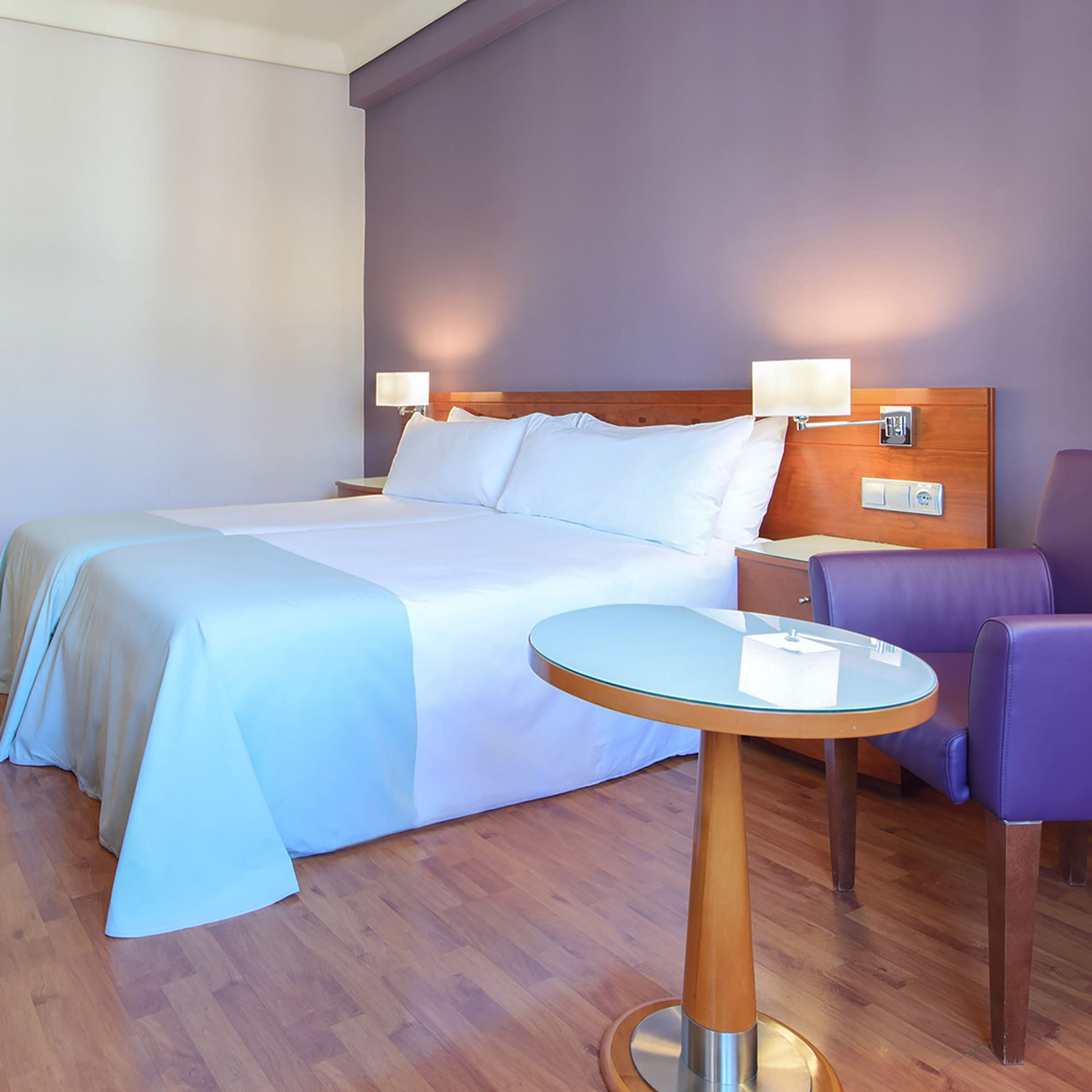 a room with a bed and purple chairs