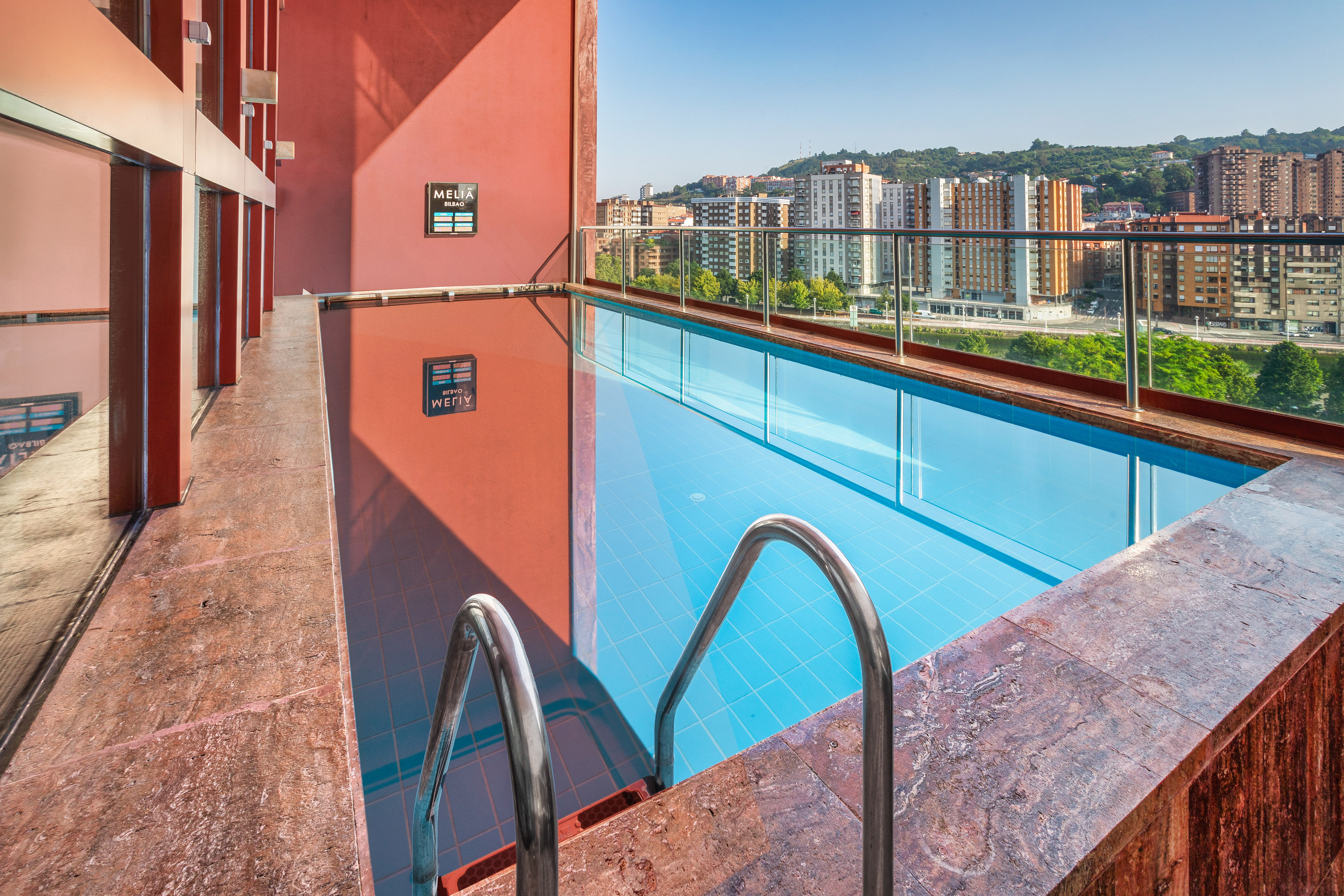 Melia Bilbao hotel's modern rooftop pool overlooking a vibrant cityscape.