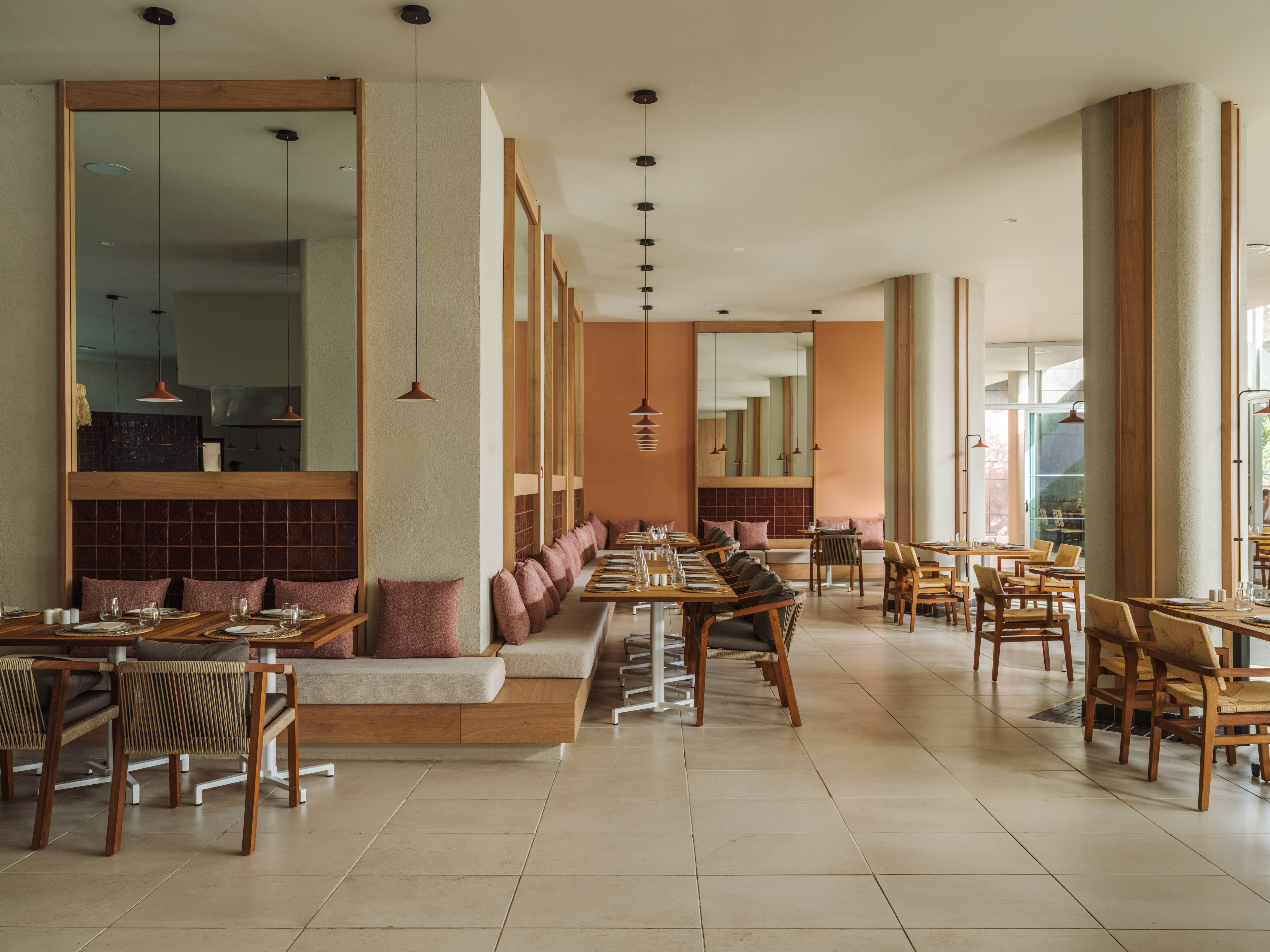 Stylish restaurant interior with wooden banquettes, set tables, and warm lighting.