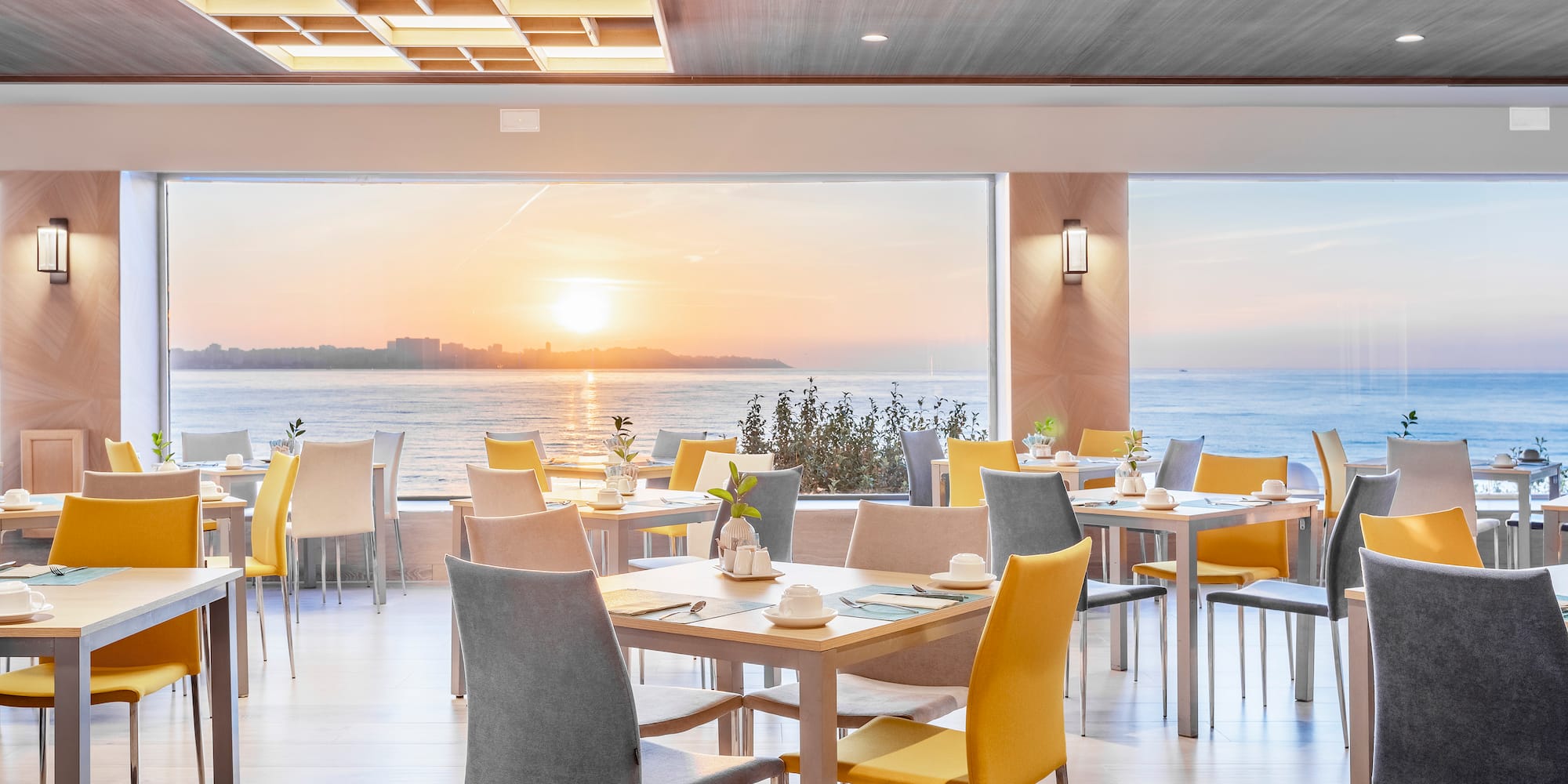 a room with tables and chairs and a large window overlooking the ocean