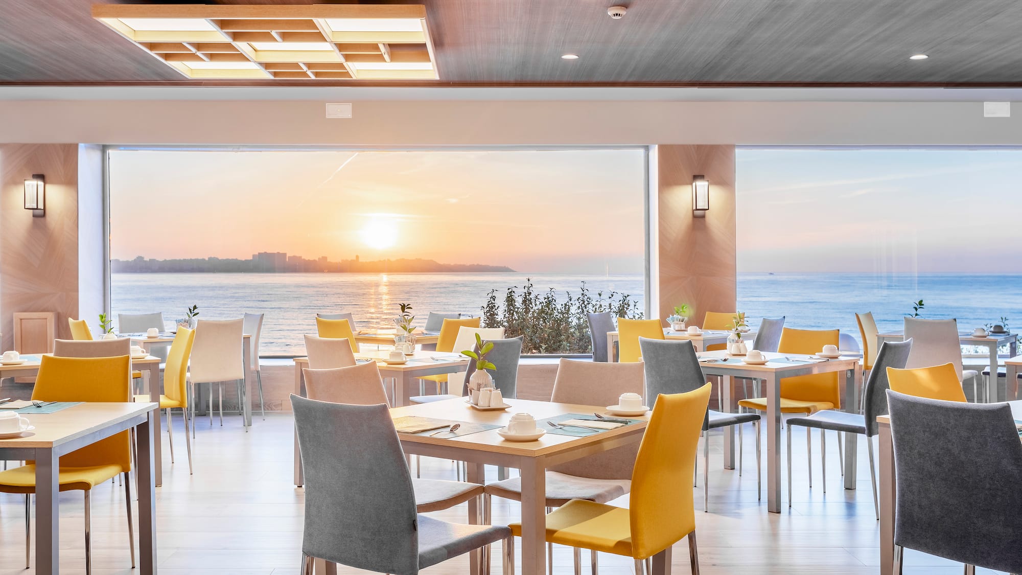 a room with tables and chairs and a large window overlooking the ocean