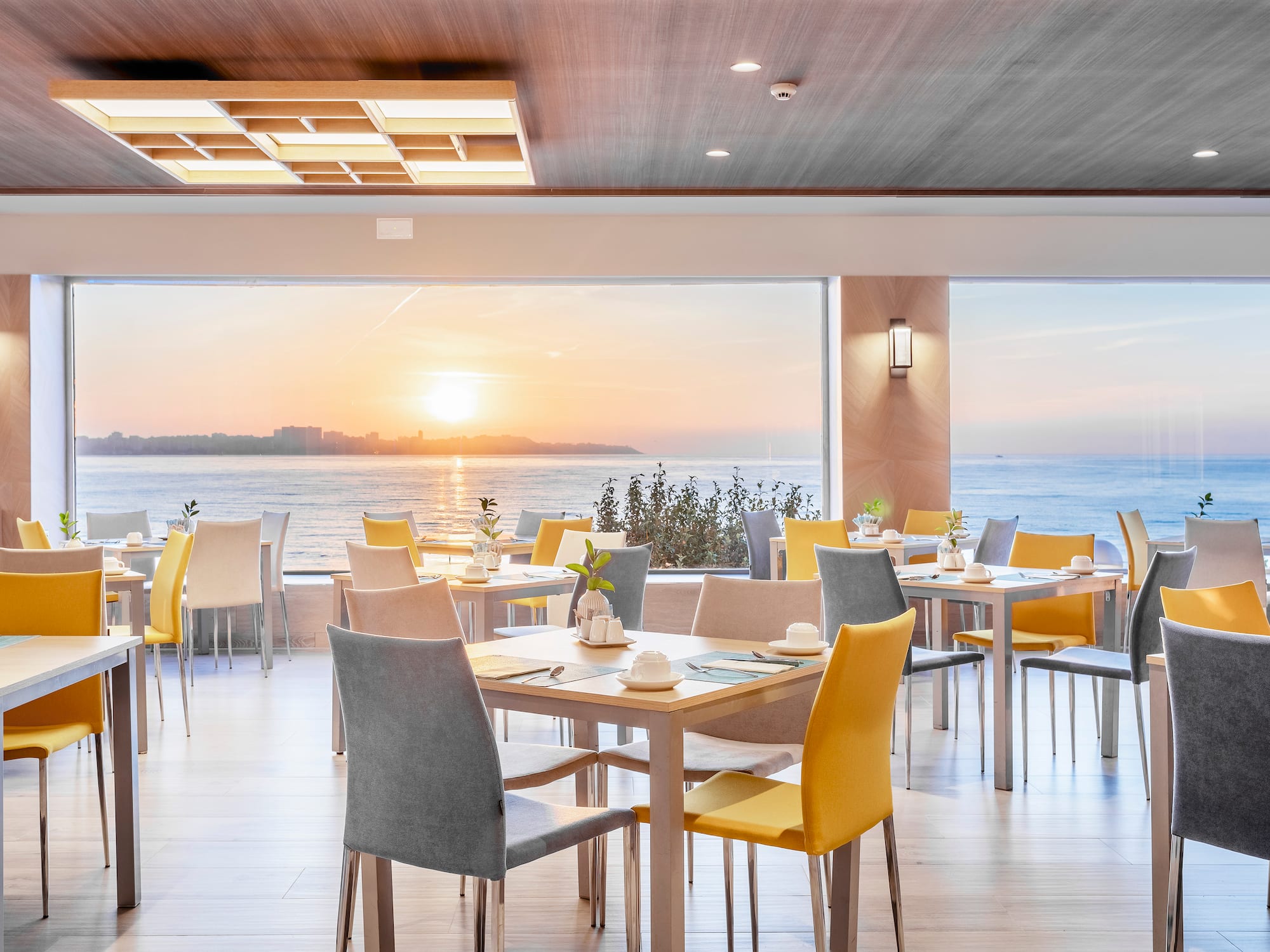 a room with tables and chairs and a large window overlooking the ocean