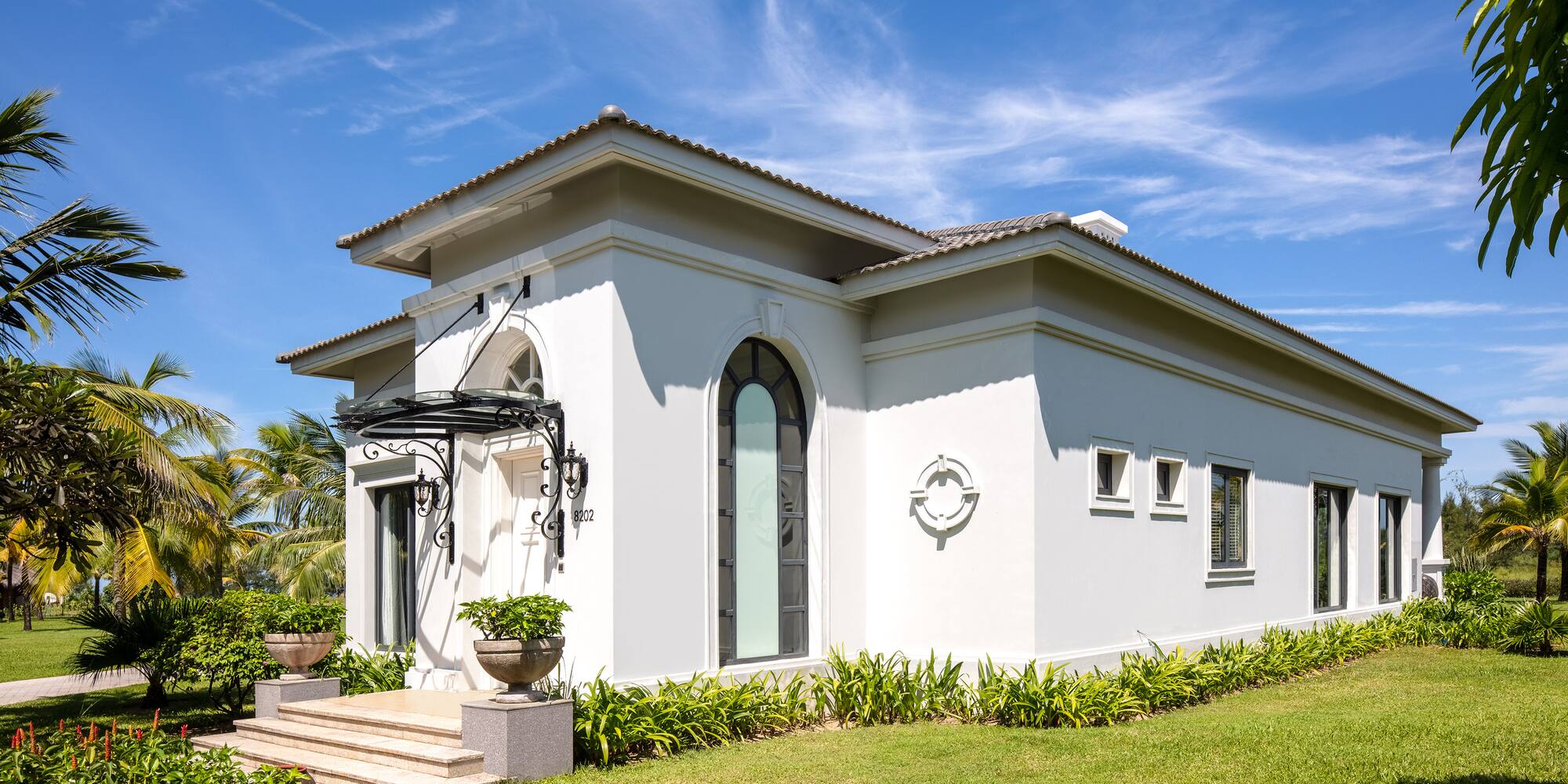 a white house with a green lawn and blue sky