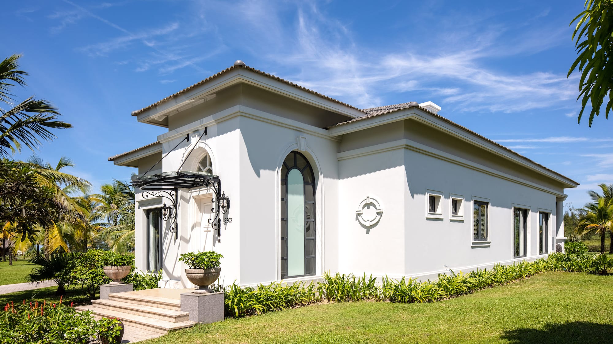 a white house with a green lawn and blue sky