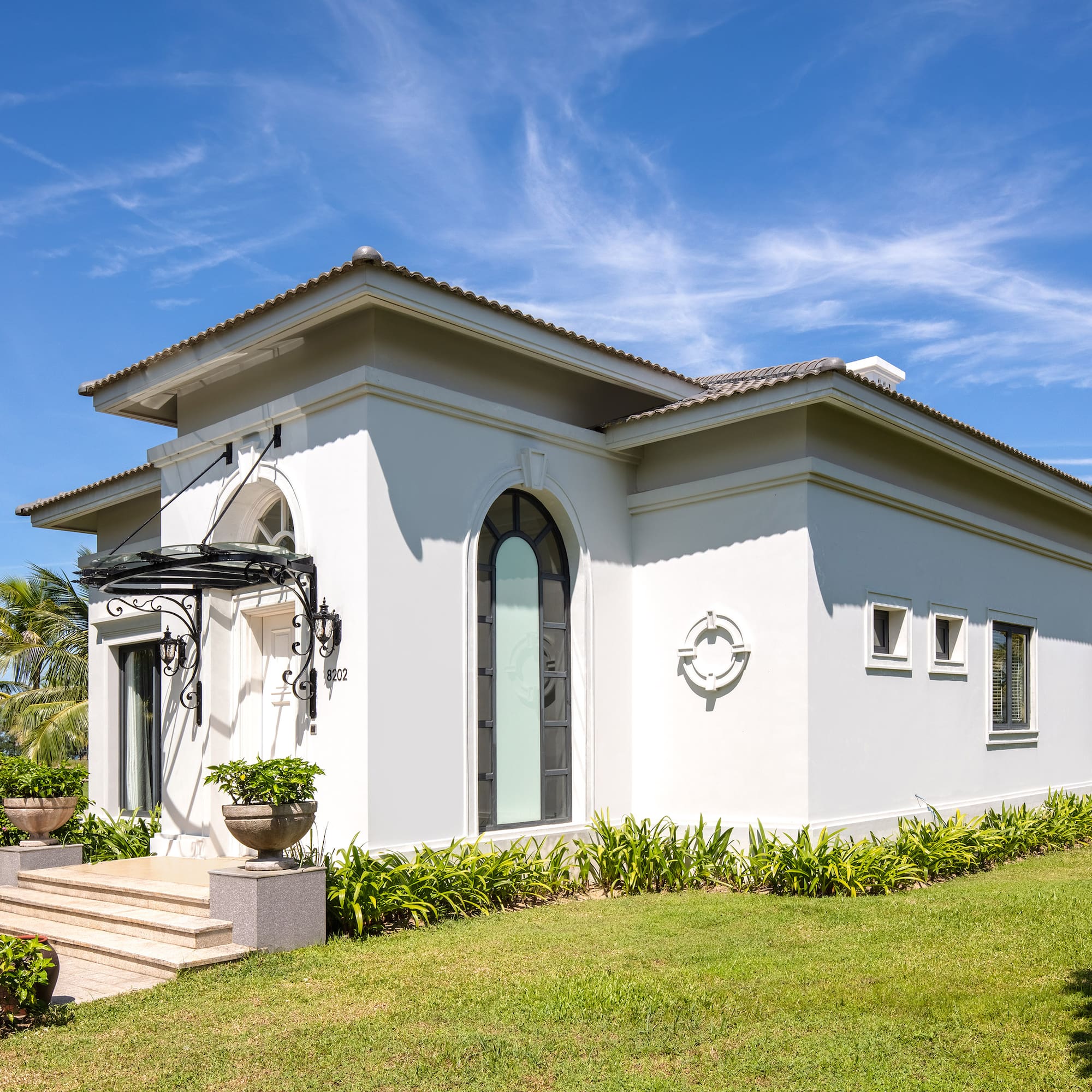 a white house with a green lawn and blue sky