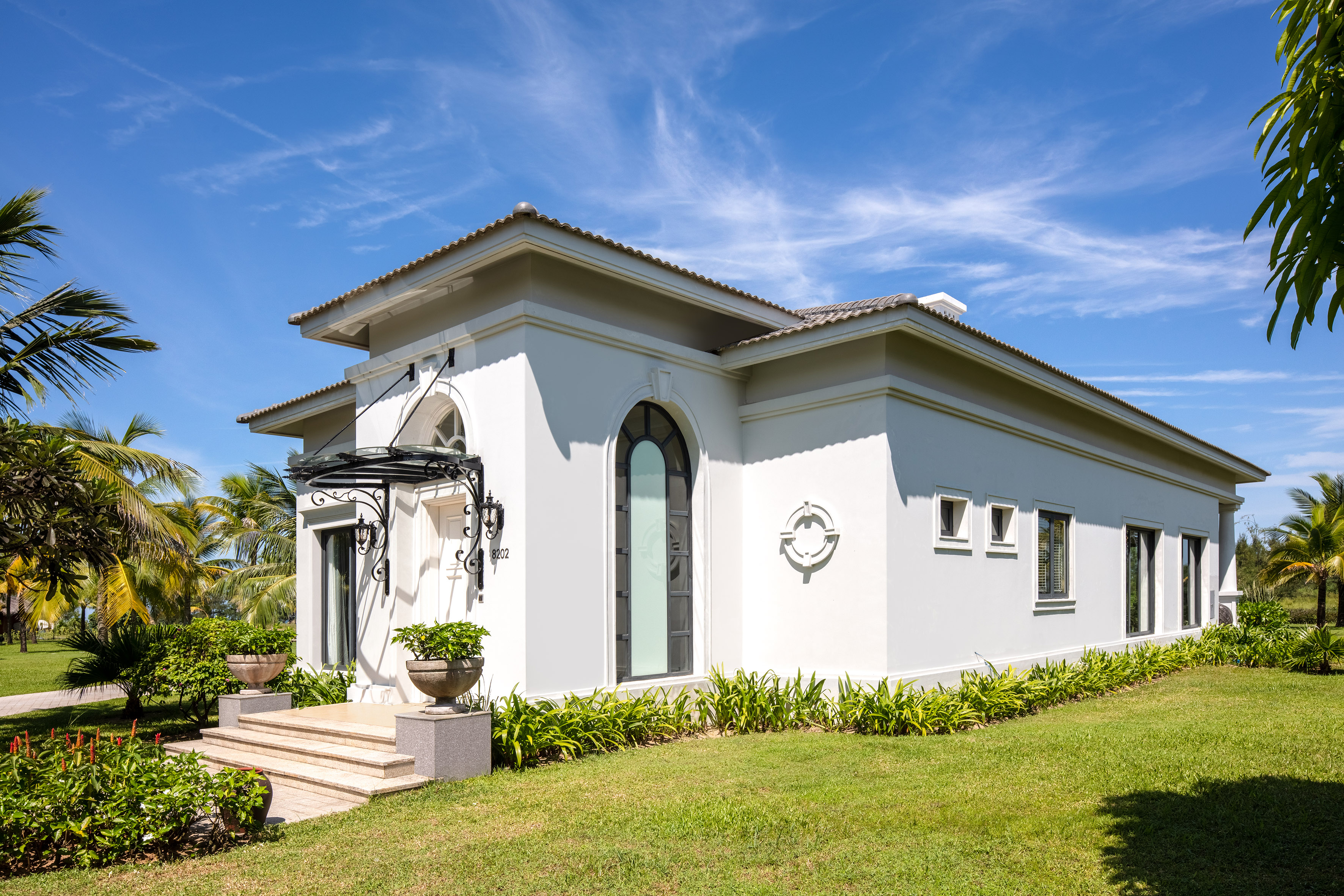a white house with a green lawn and blue sky