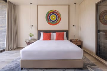 a bed with white sheets and red pillows