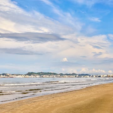 a beach with a body of water and buildings in the background