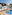 Sunny resort pool with thatched bar and shaded outdoor dining areas.