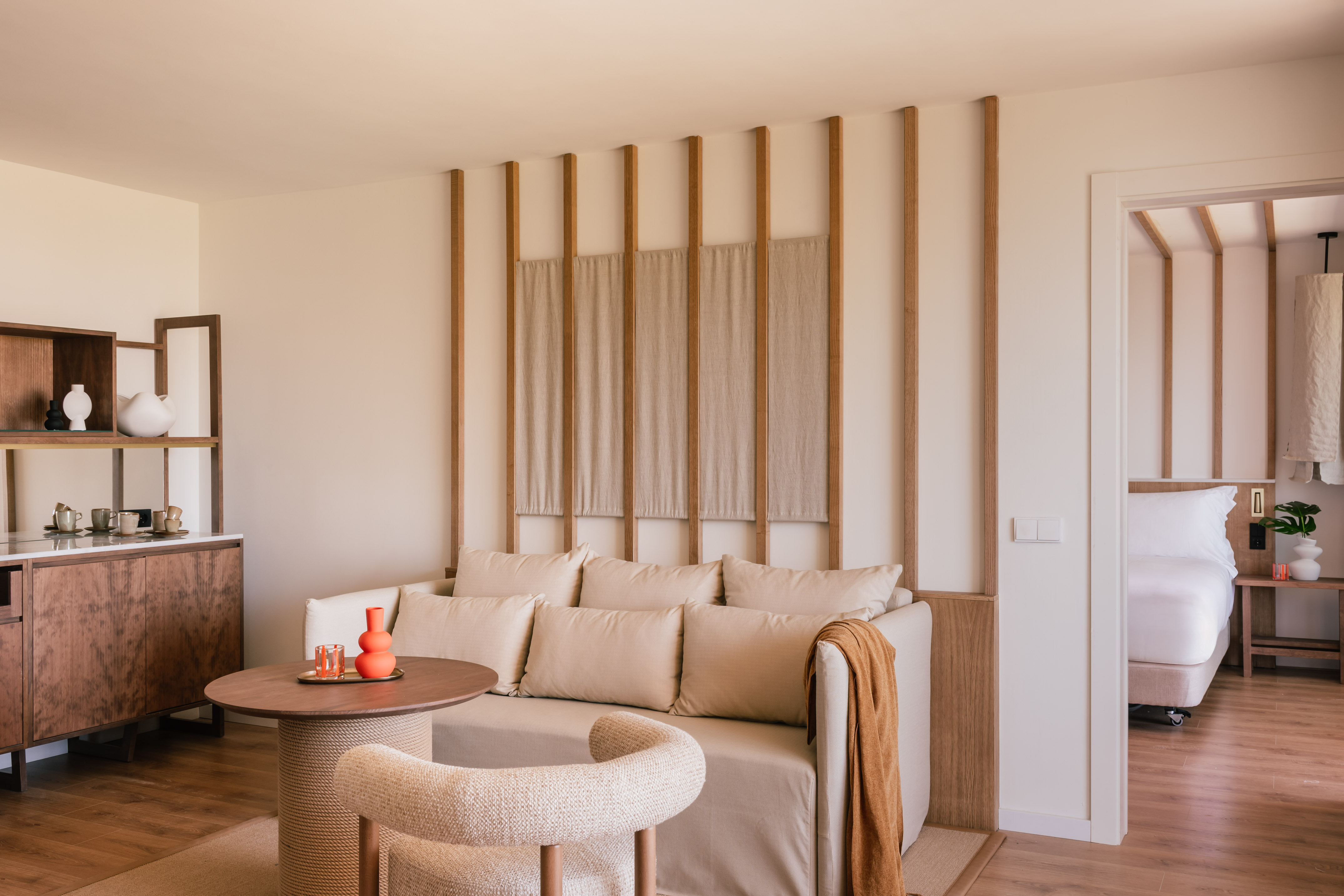 Modern hotel suite living room with cream sofa and minimalist wooden accents.
