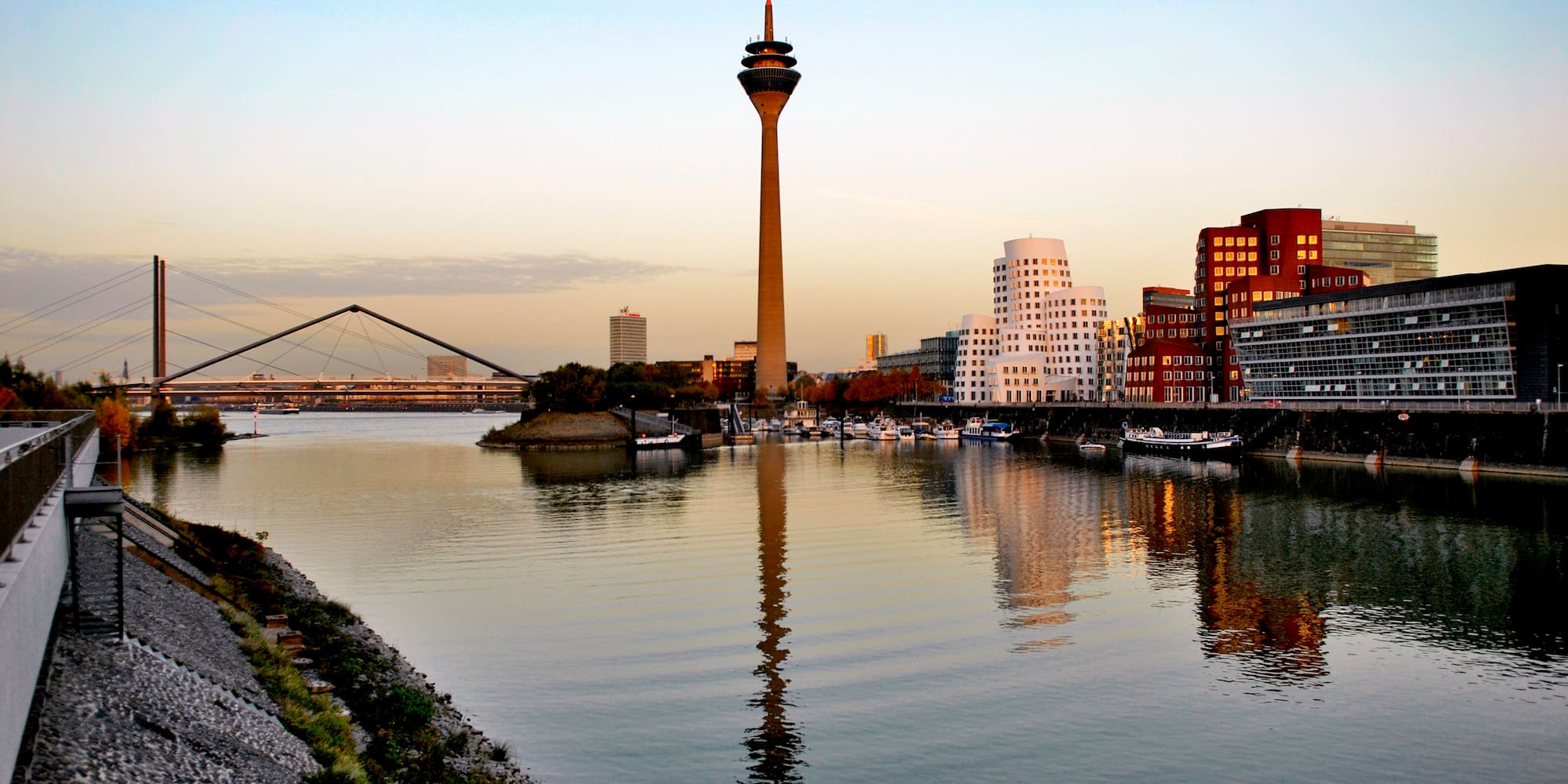 Düsseldorf Rheinturm, Gehry buildings, and Rhine river reflecting sunset colors.