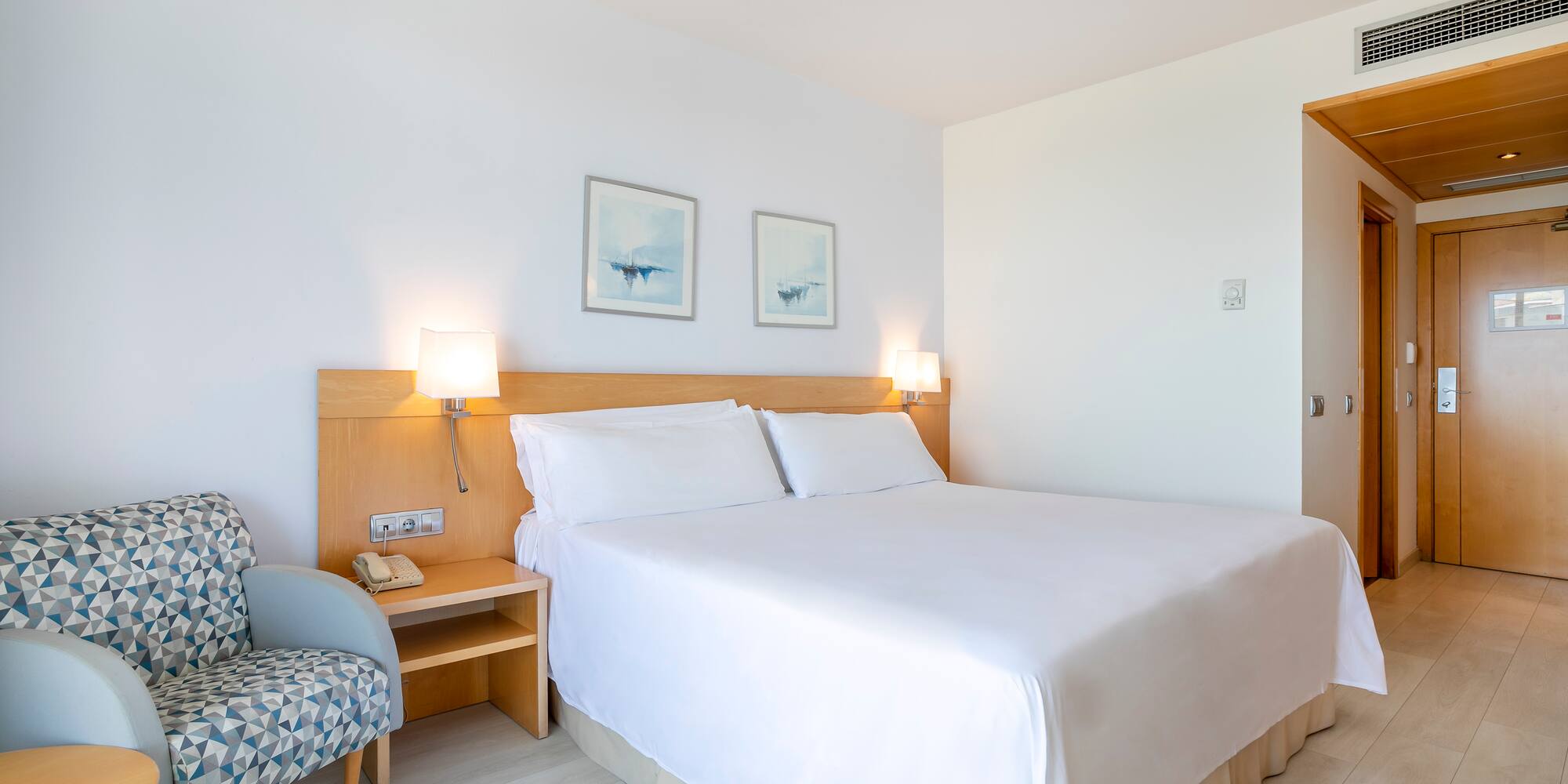 a bed with white sheets and a wood headboard in a room