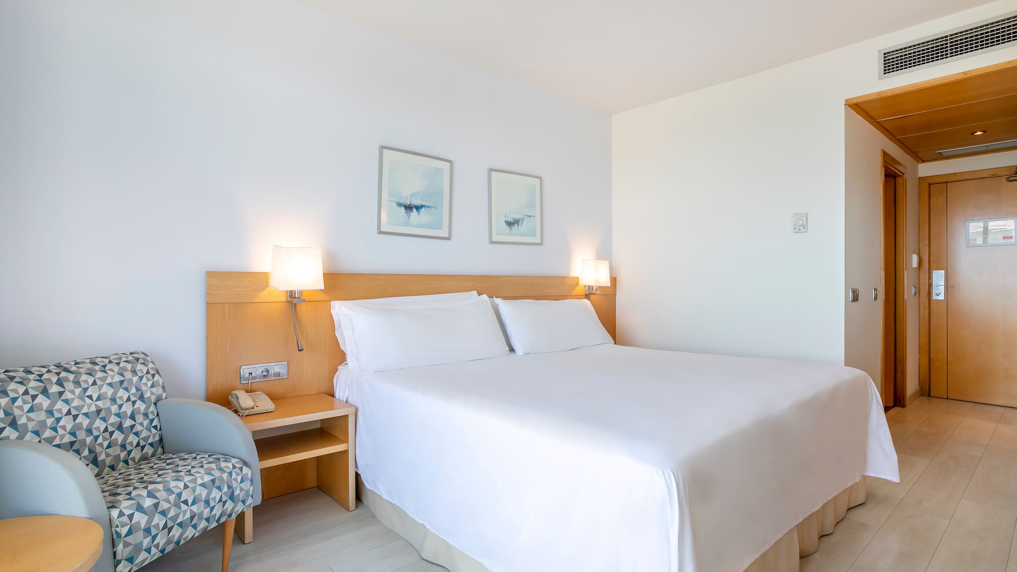 a bed with white sheets and a wood headboard in a room