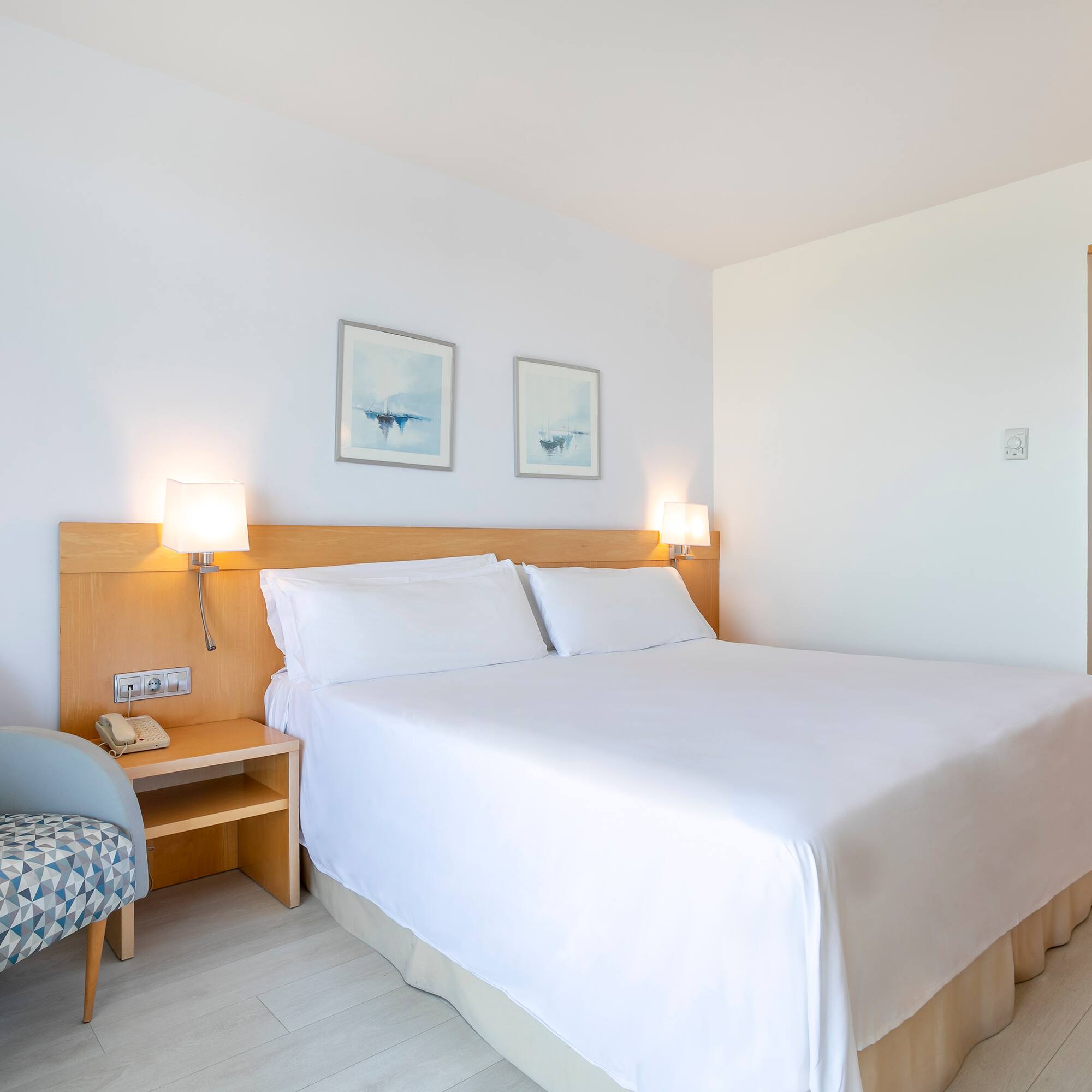 a bed with white sheets and a wood headboard in a room