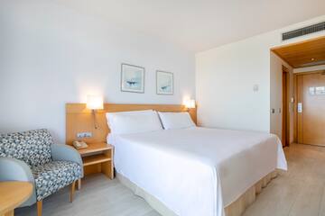 a bed with white sheets and a wood headboard in a room