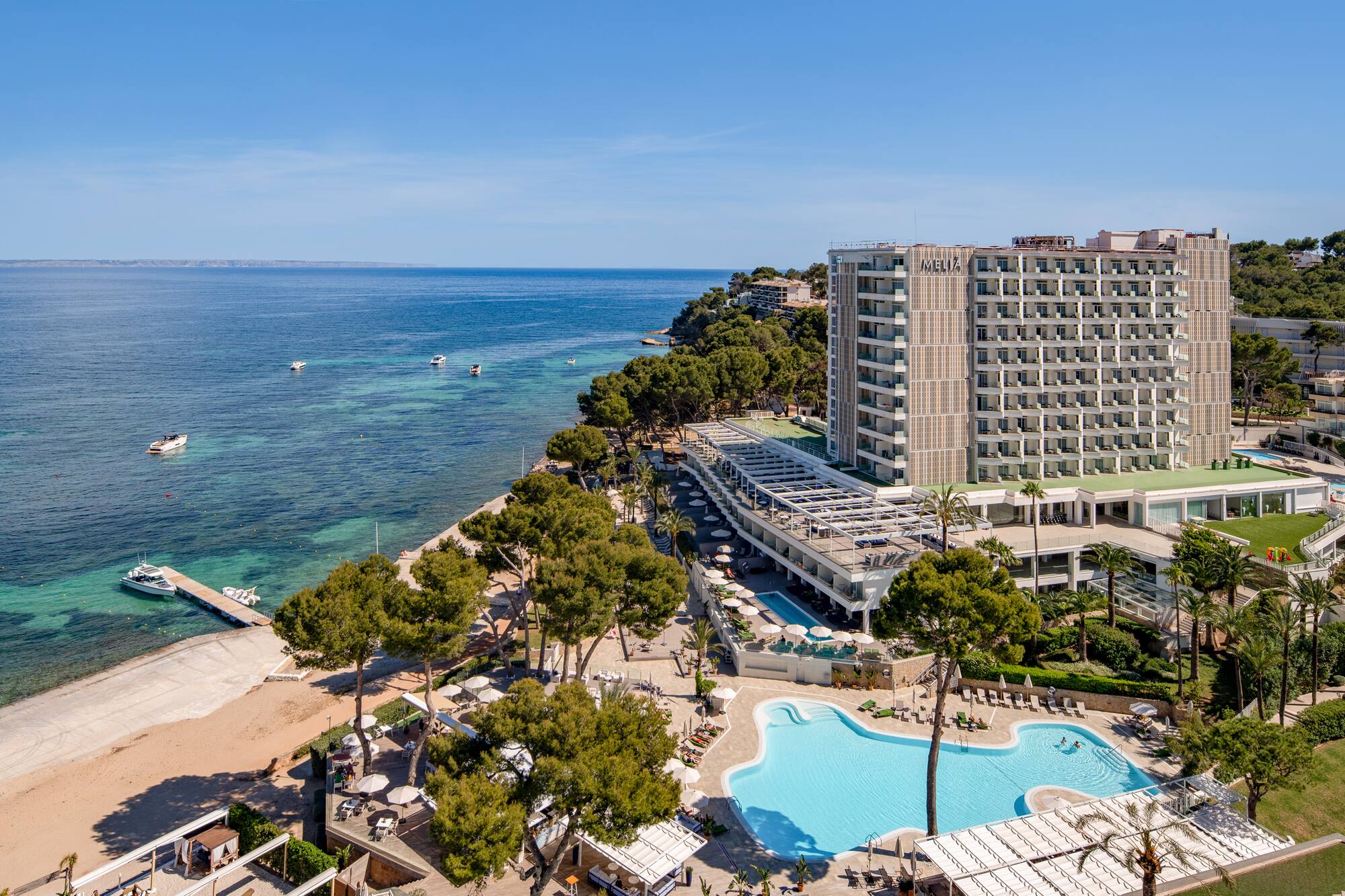 Melia beachfront resort with pools, sandy beach, and boats in clear ocean.