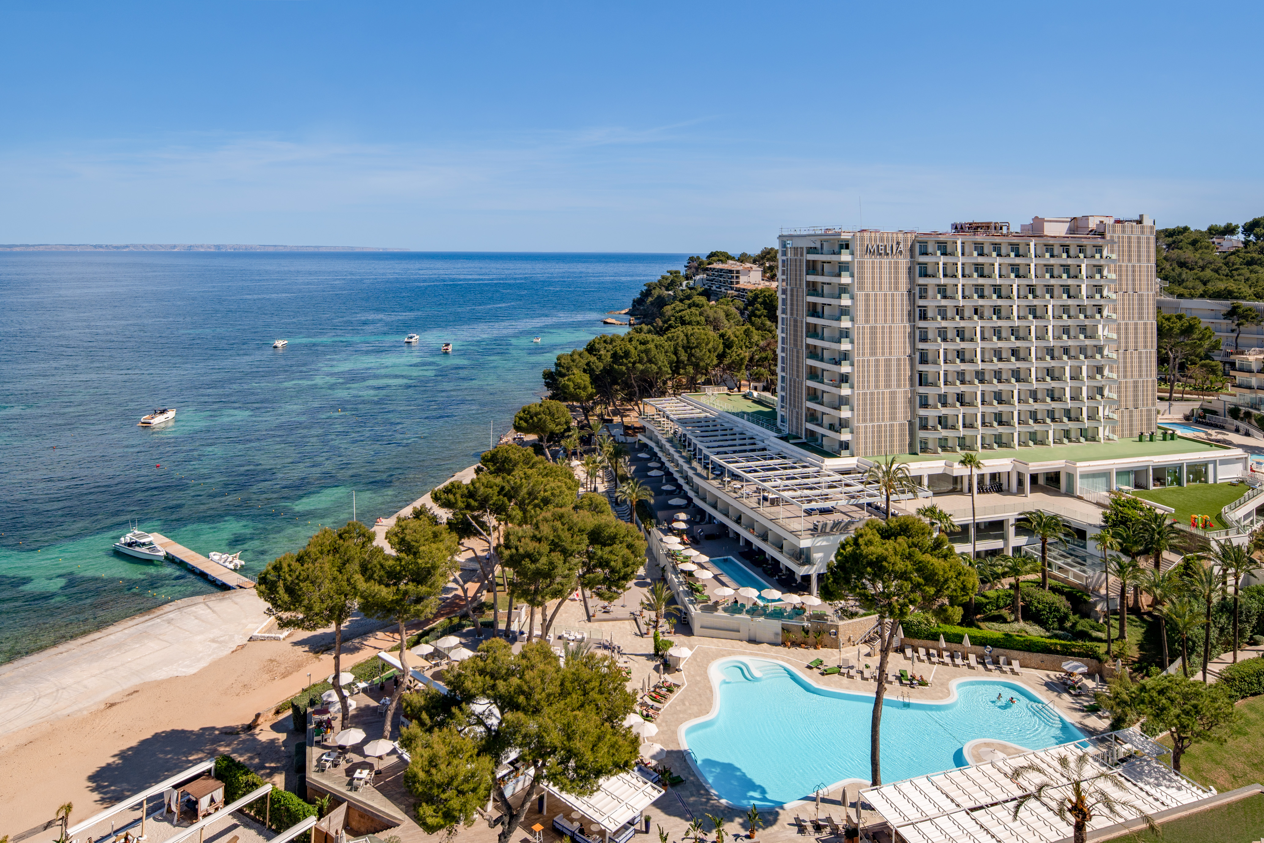 Melia beachfront resort with pools, sandy beach, and boats in clear ocean.