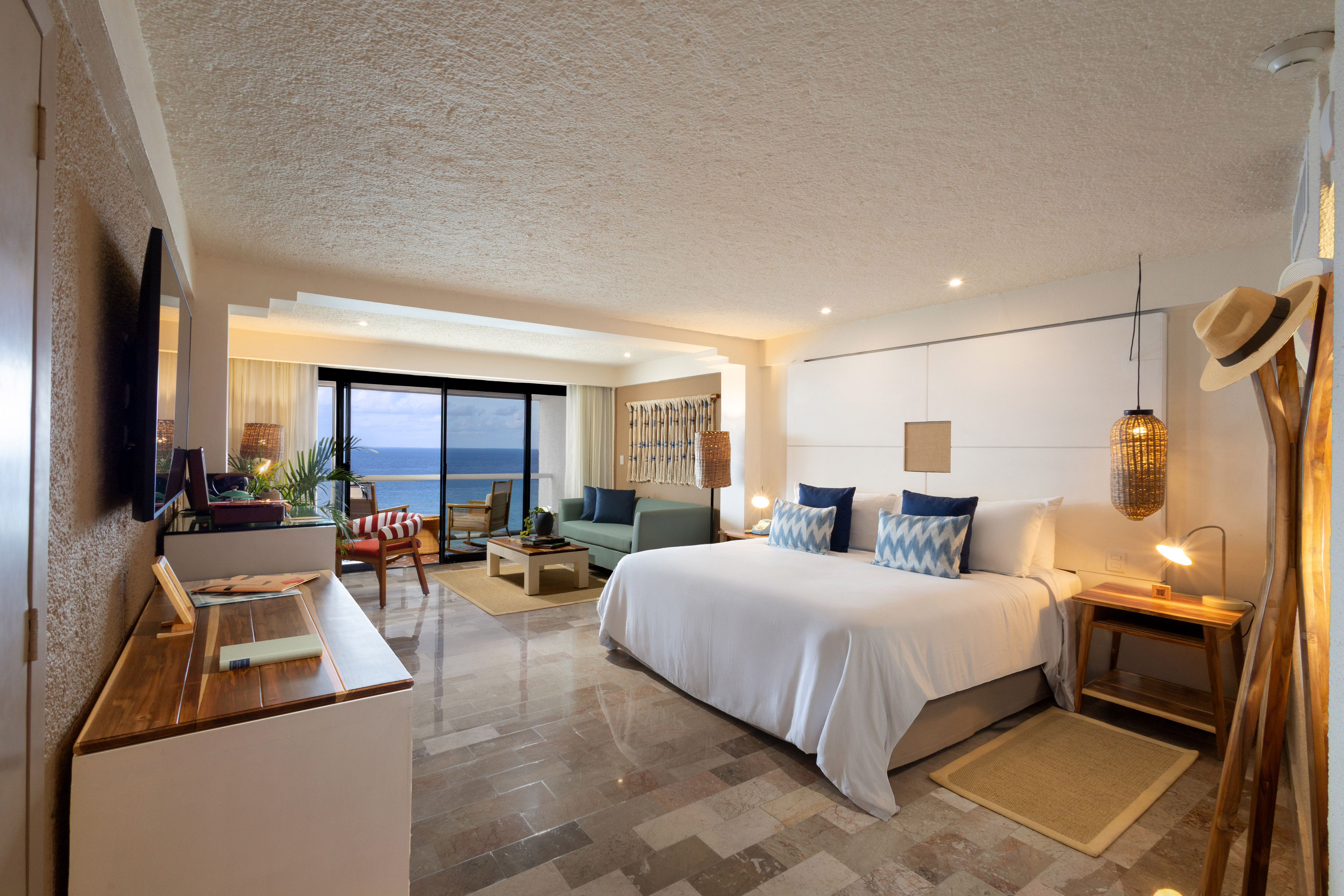 Oceanfront hotel suite with king bed, living area, and balcony view.
