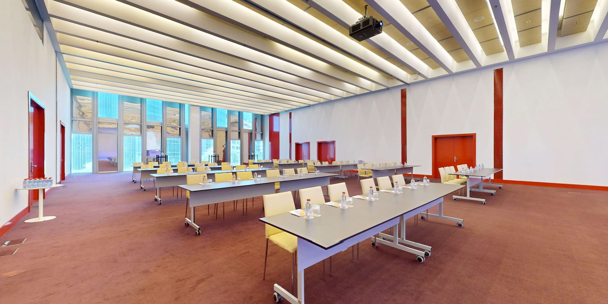 Spacious modern conference room with tables, chairs, projector, and large windows.