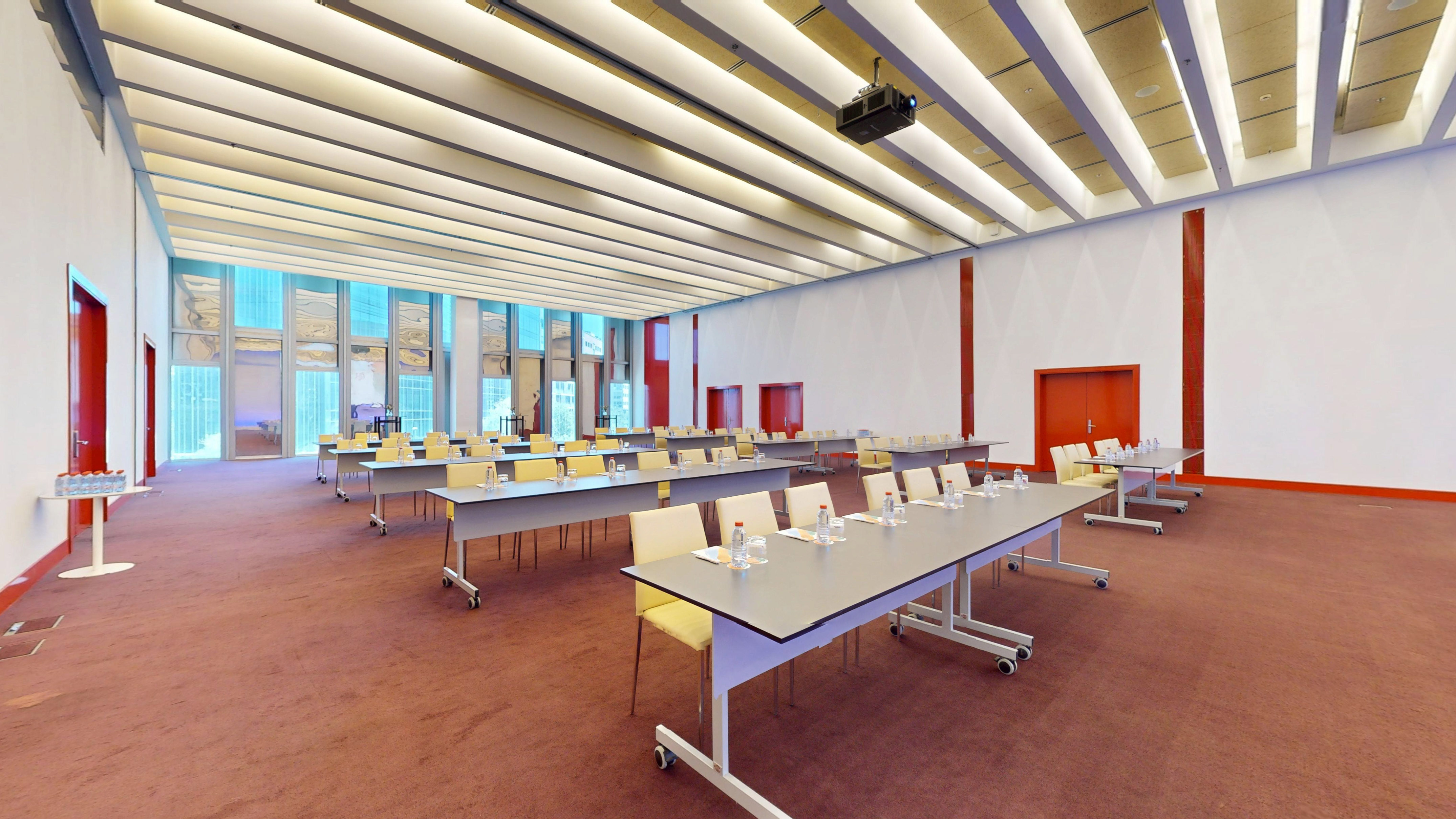 Spacious modern conference room with tables, chairs, projector, and large windows.