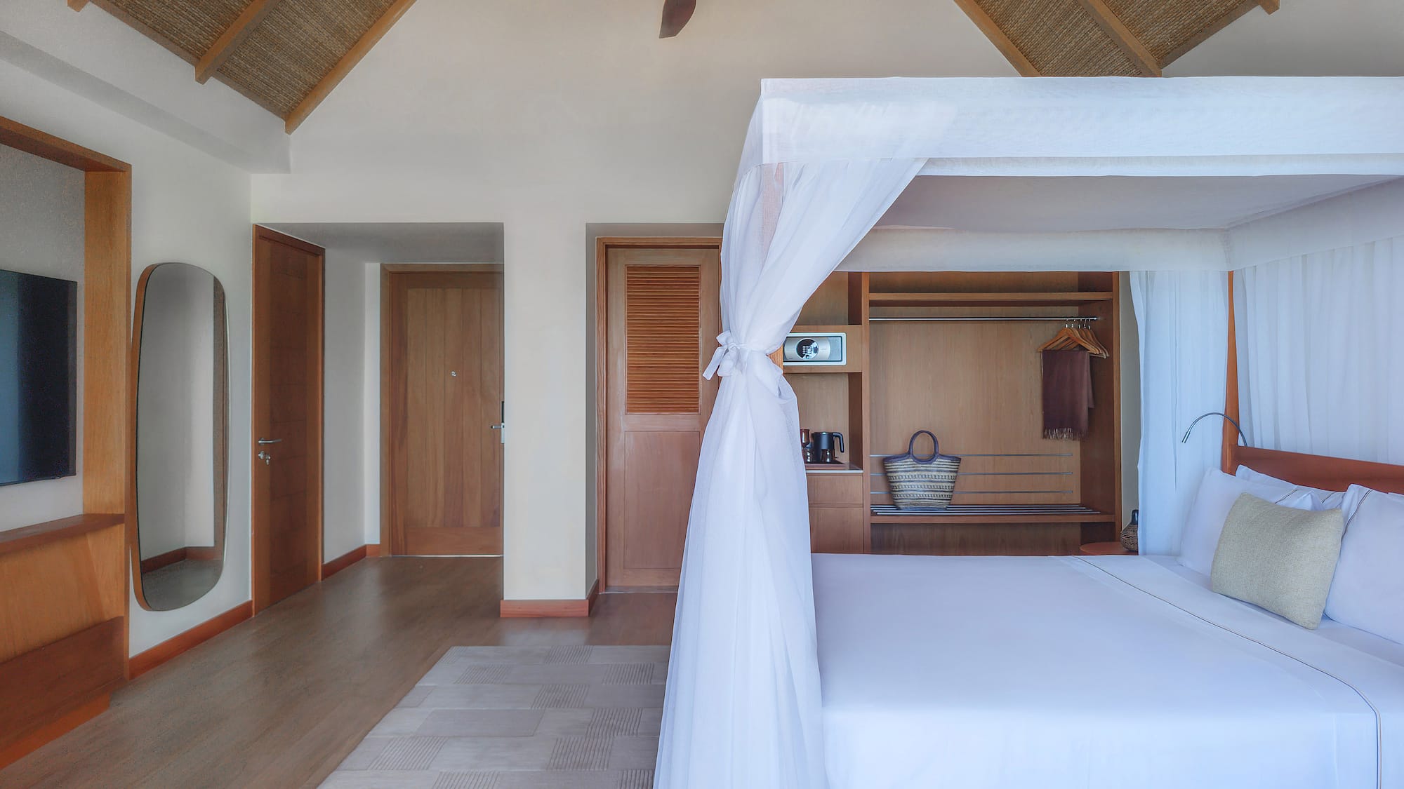 Tropical bedroom with four-poster bed, mosquito net, and vaulted straw ceiling.
