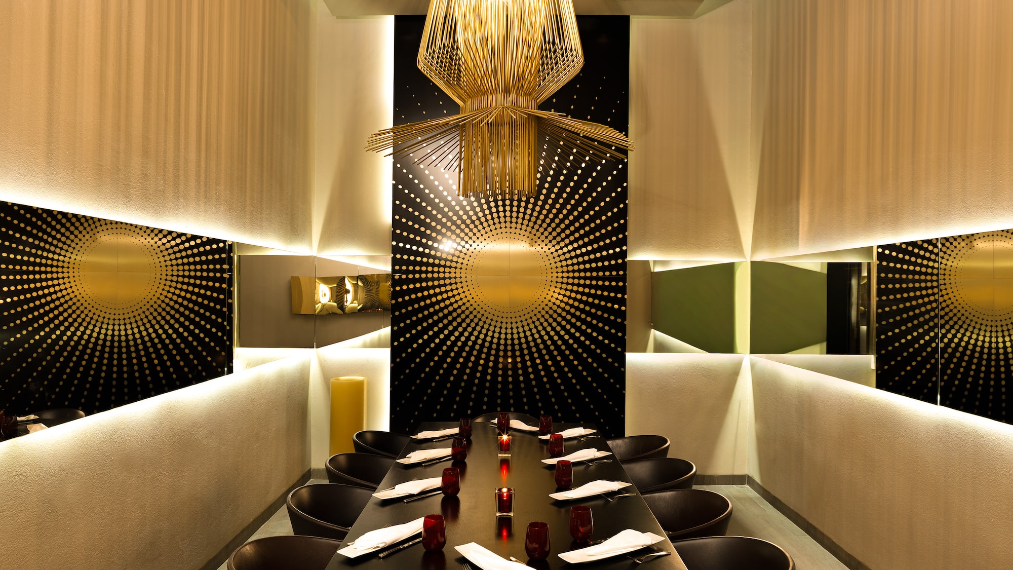 Luxurious private dining room with gold chandelier, sunburst wall, and elegant table.