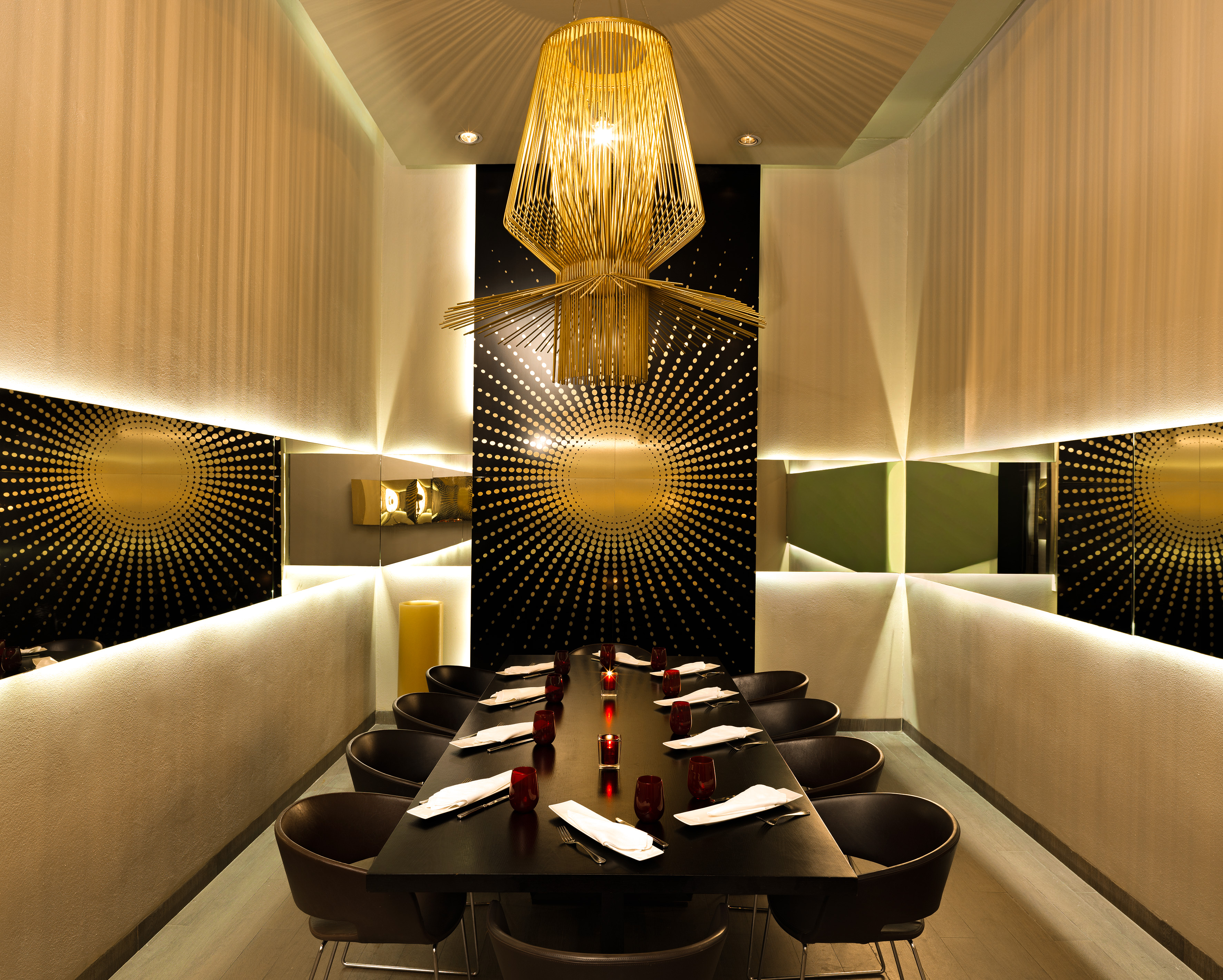 Luxurious private dining room with gold chandelier, sunburst wall, and elegant table.