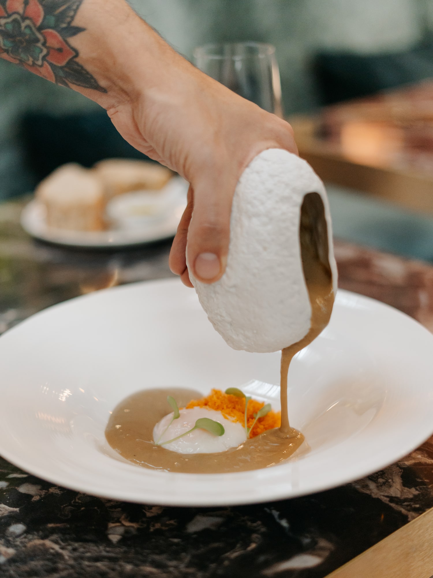 a person pouring a white object over a white plate of food