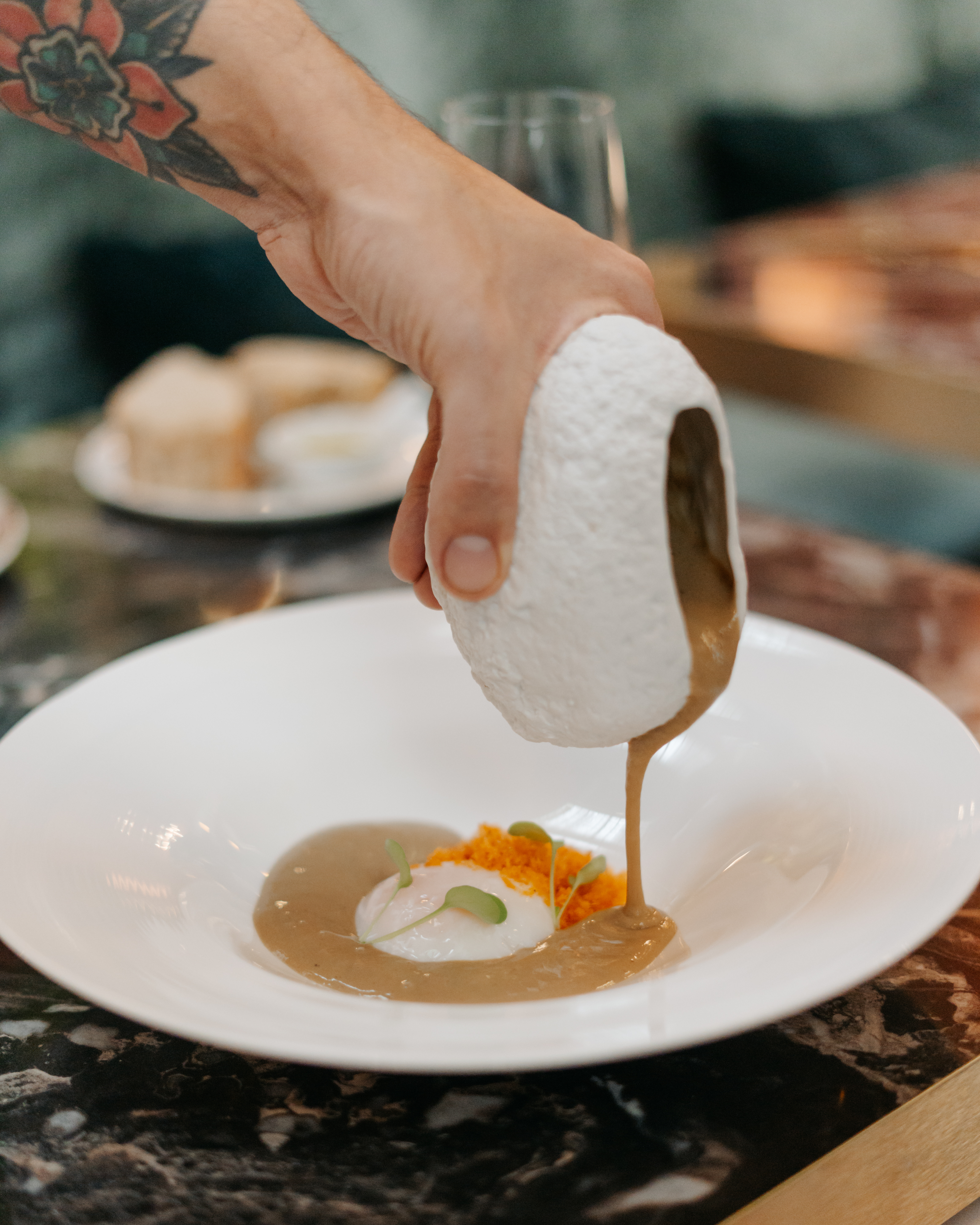 a person pouring a white object over a white plate of food