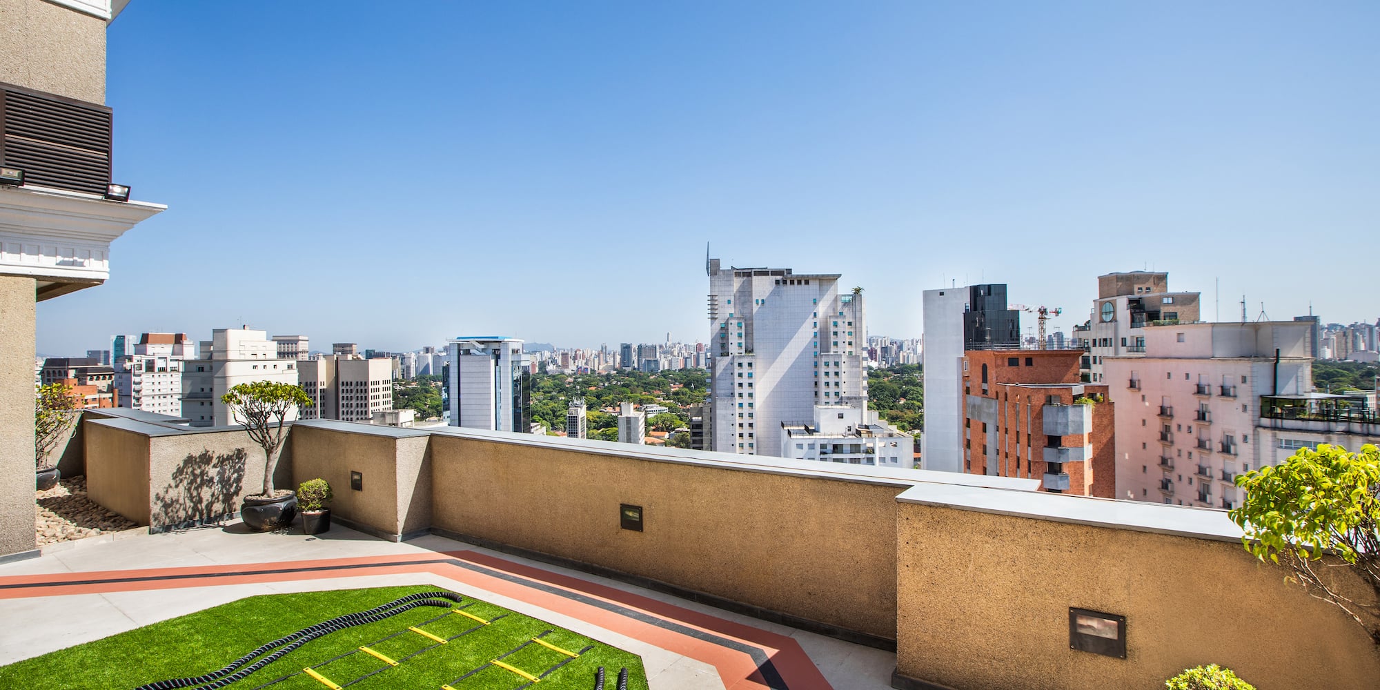 a rooftop with a green lawn and a city skyline