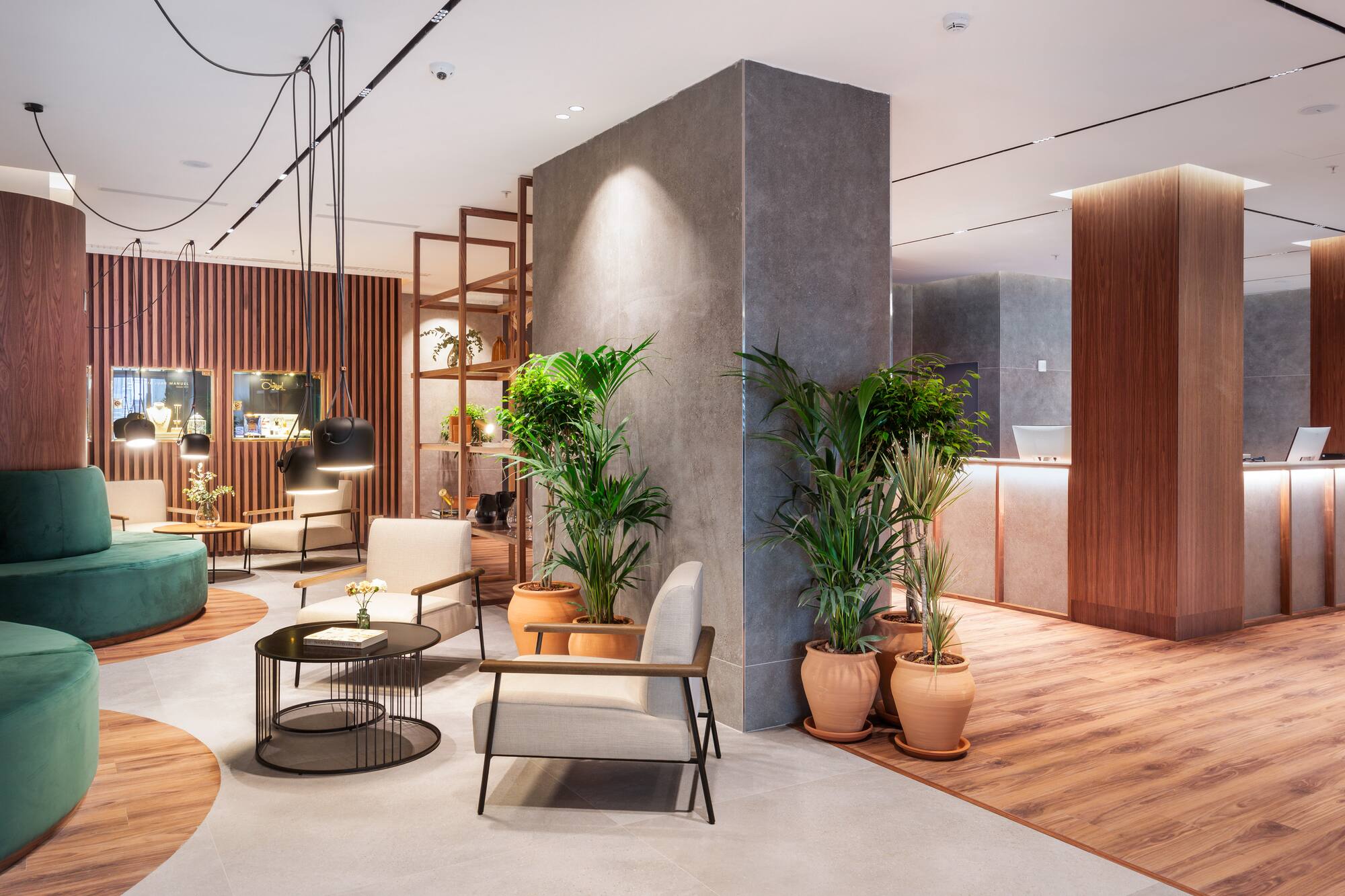 Modern hotel lobby lounge with green seating, potted plants, wood, and concrete.