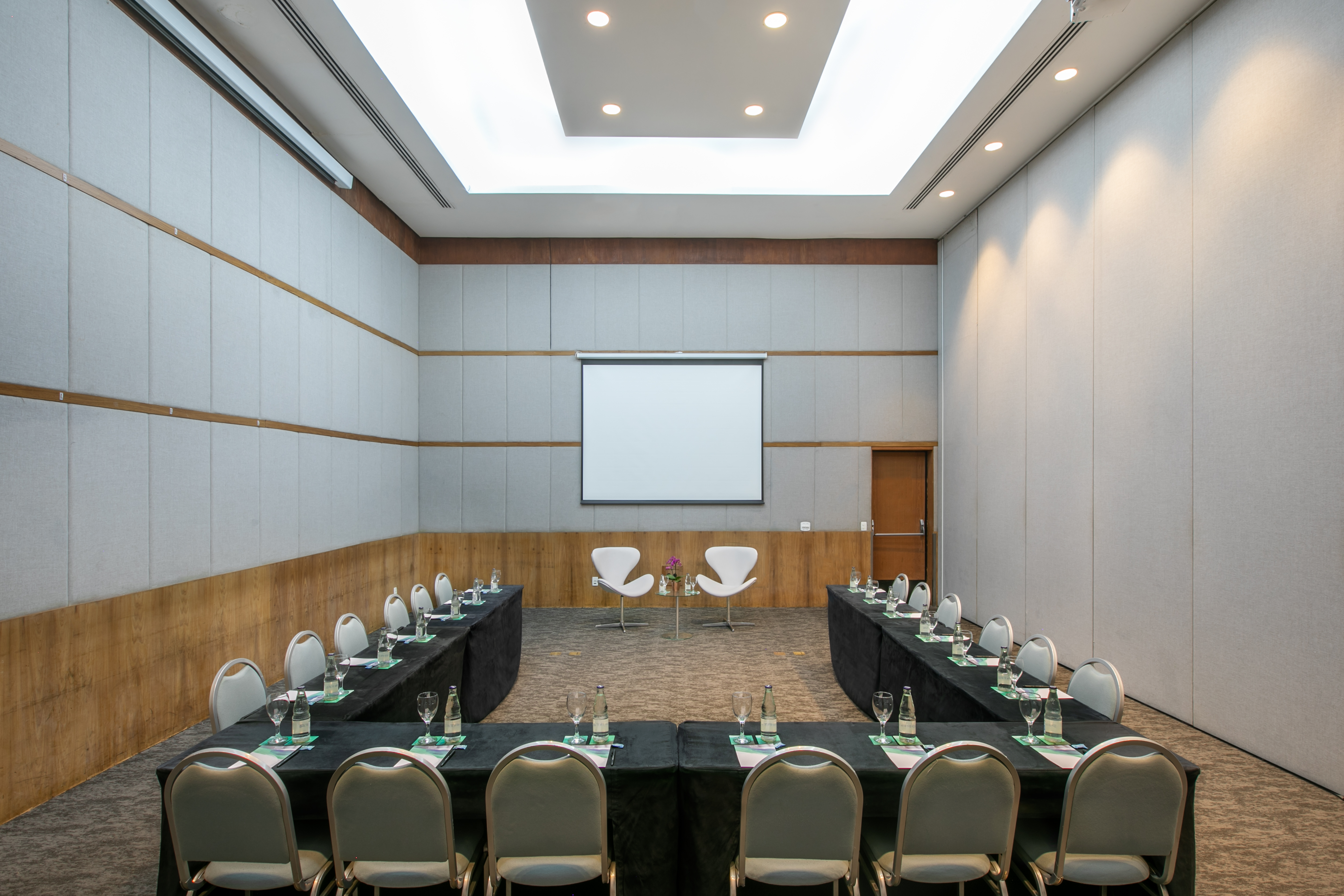Modern U-shaped conference room with projector screen and tables for meetings.
