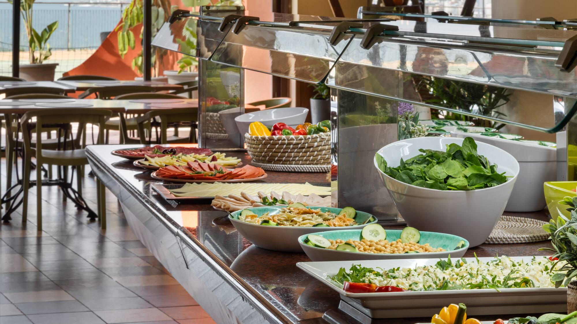 Fresh resort buffet with salads, sliced meats, cheeses, and an ocean view.