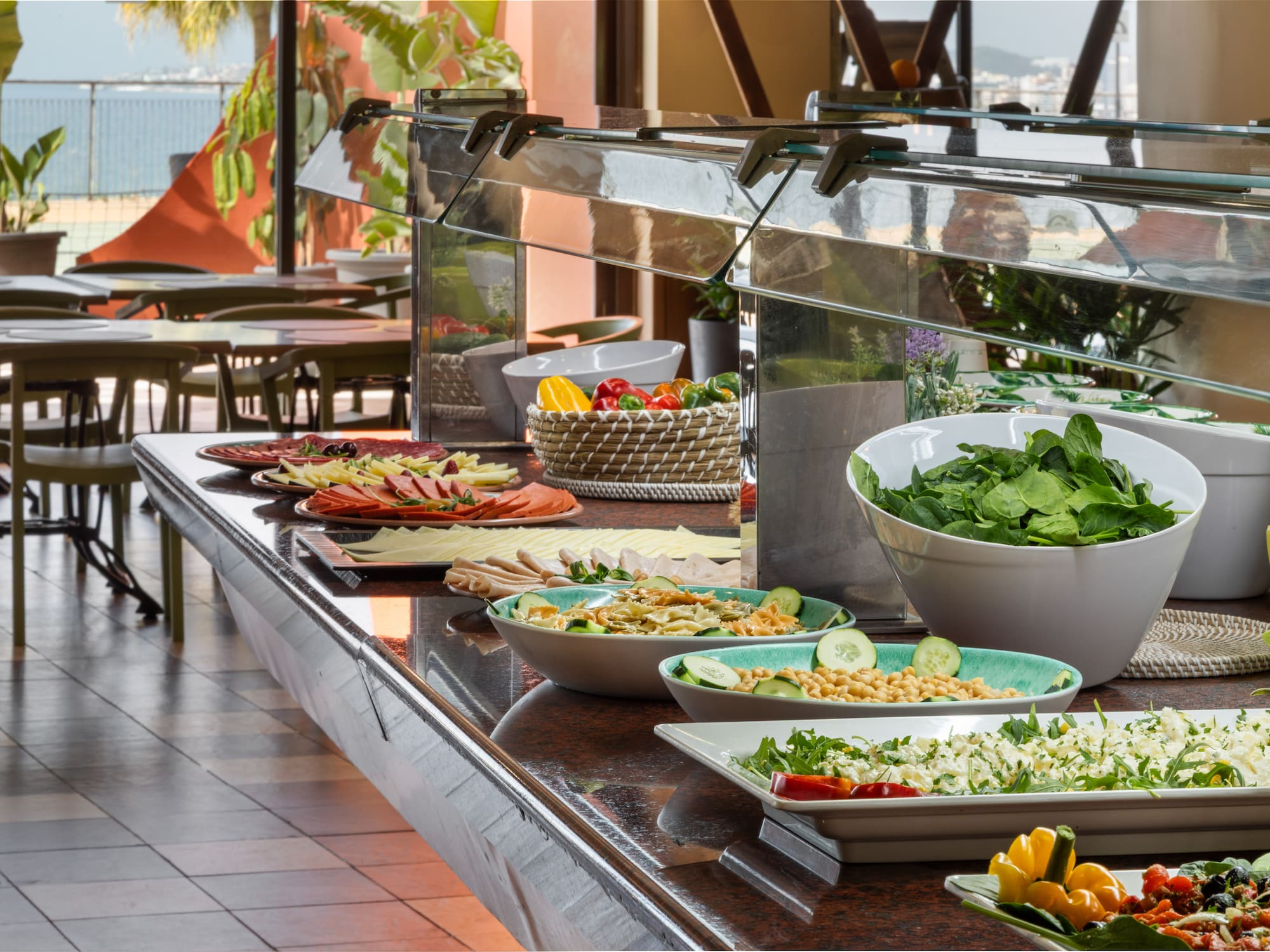Hotel buffet with fresh salads, cold cuts, and pasta overlooking the sea.