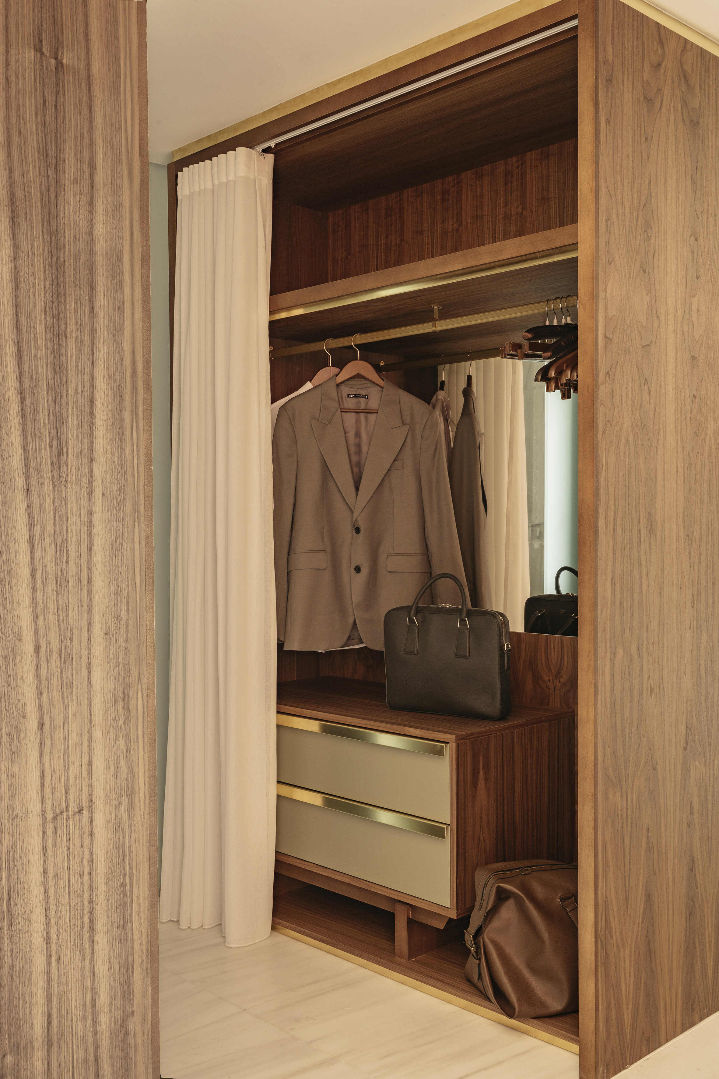Walnut wood wardrobe with blazer, briefcase, drawers, and gold trim.