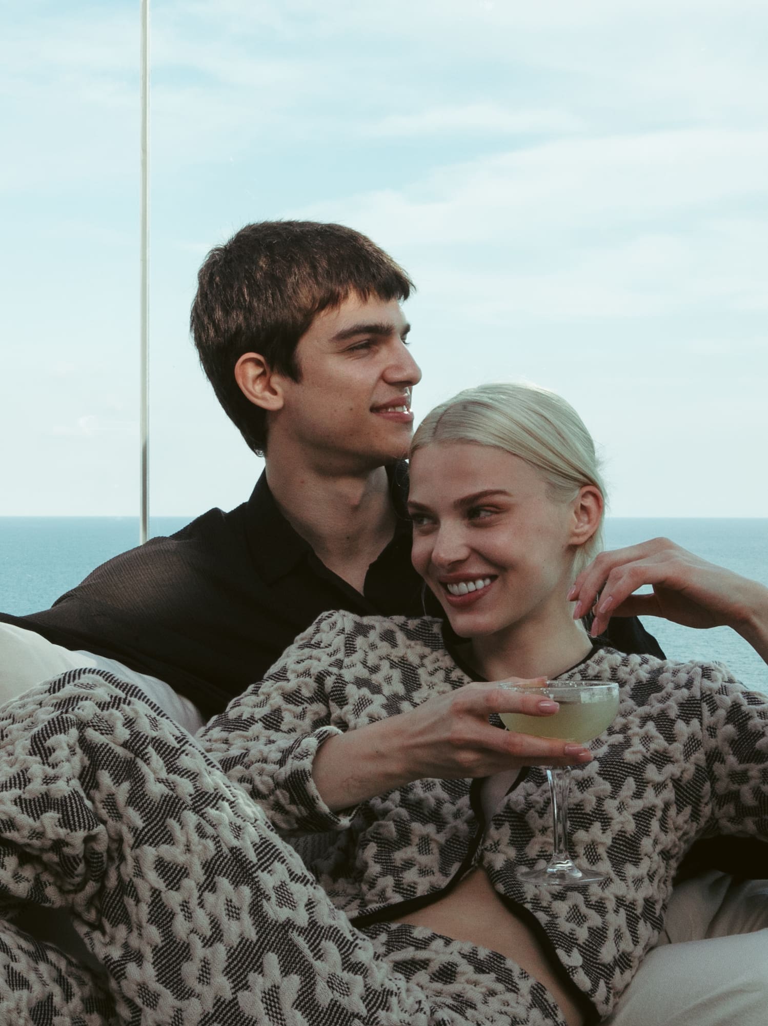 a man and woman sitting on a couch with drinks