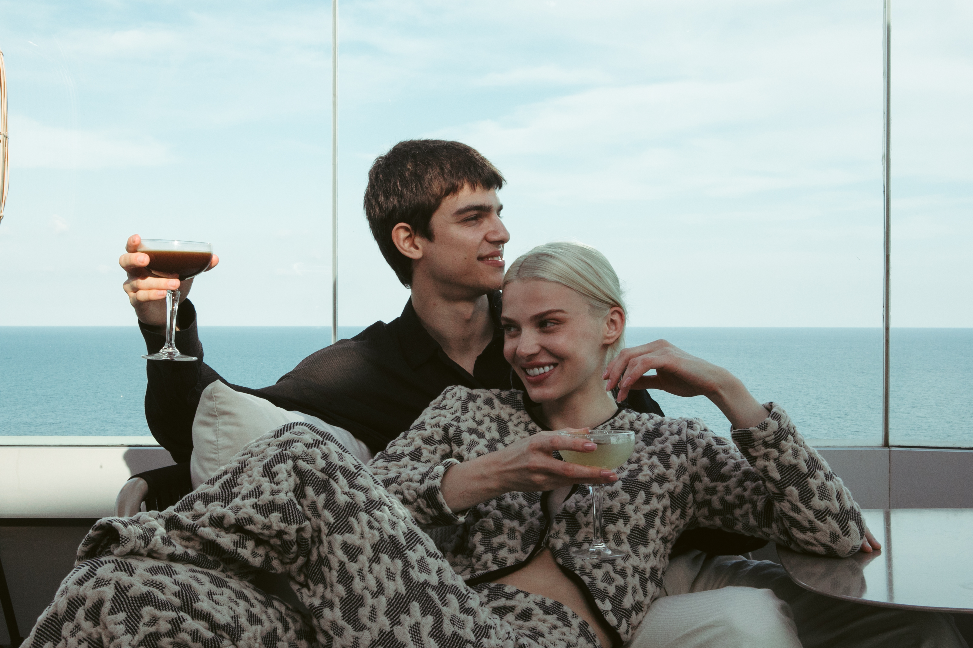 a man and woman sitting on a couch with drinks