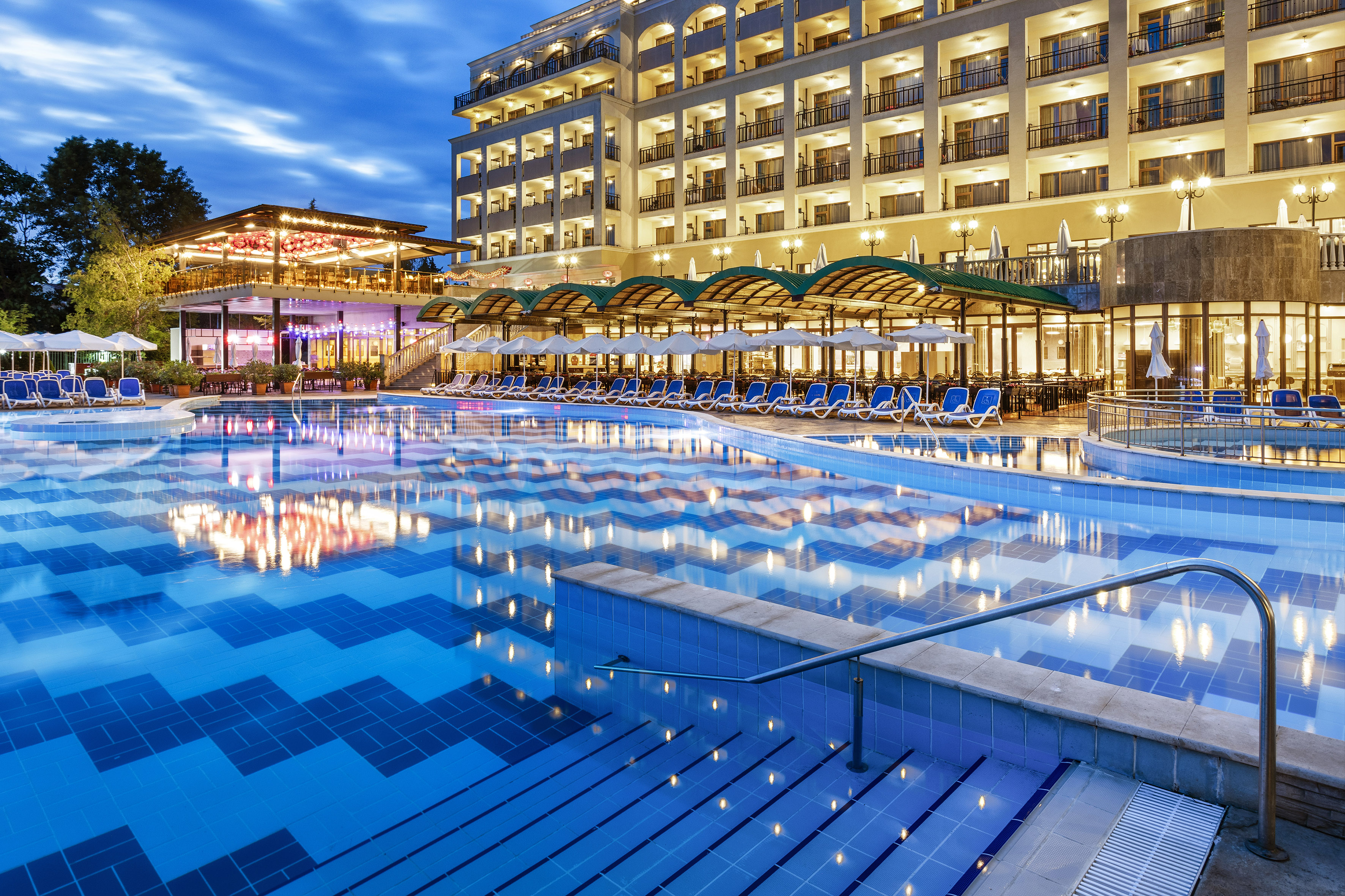 a pool with chairs and a building in the background