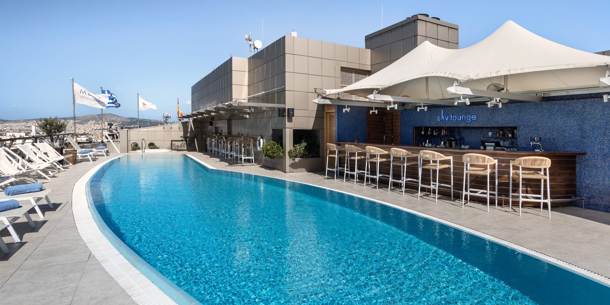 Rooftop pool, Sky Lounge bar, sun loungers overlooking Athens cityscape.