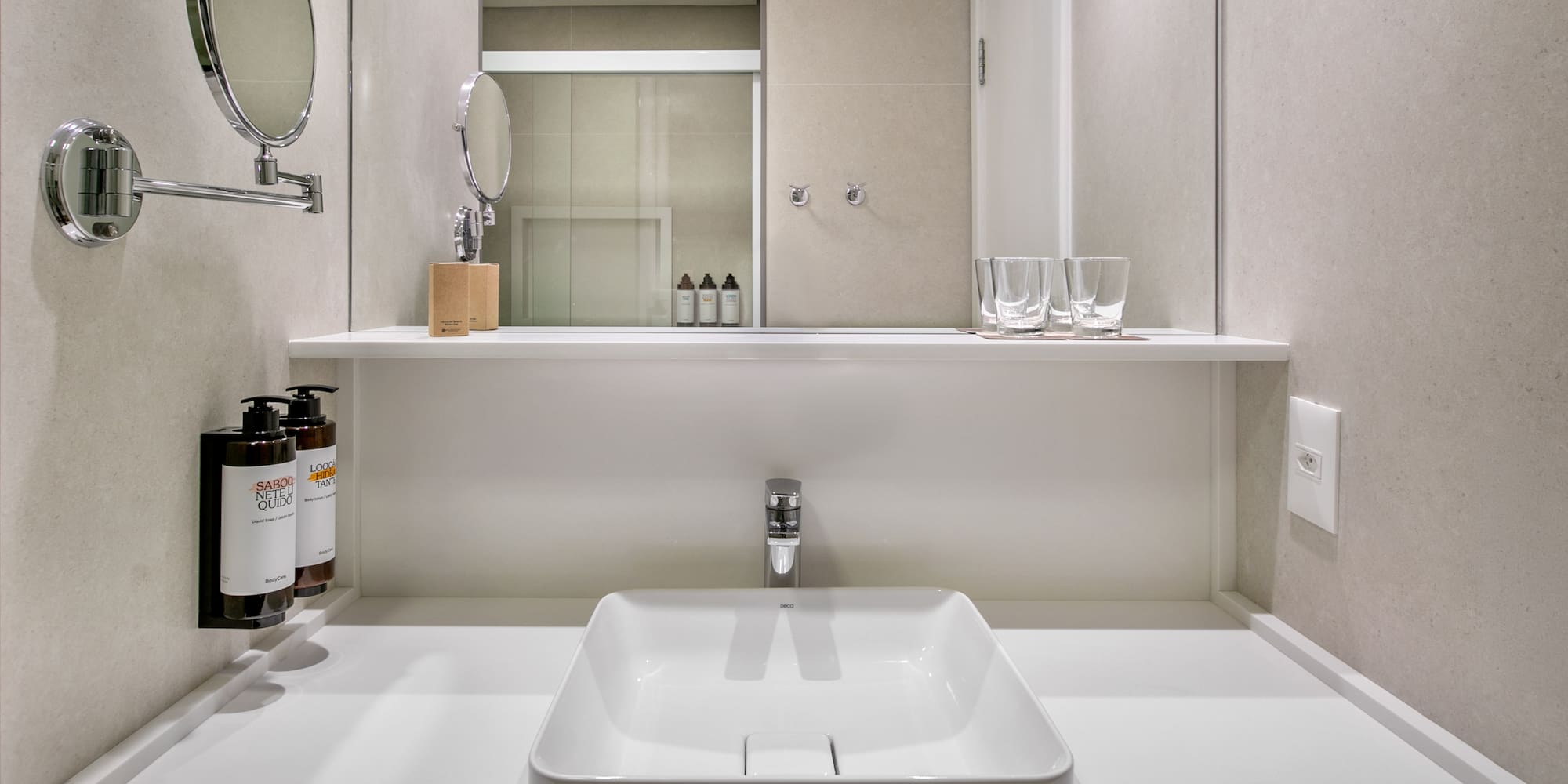 Modern hotel bathroom vanity with square sink, chrome faucet, and mirror.