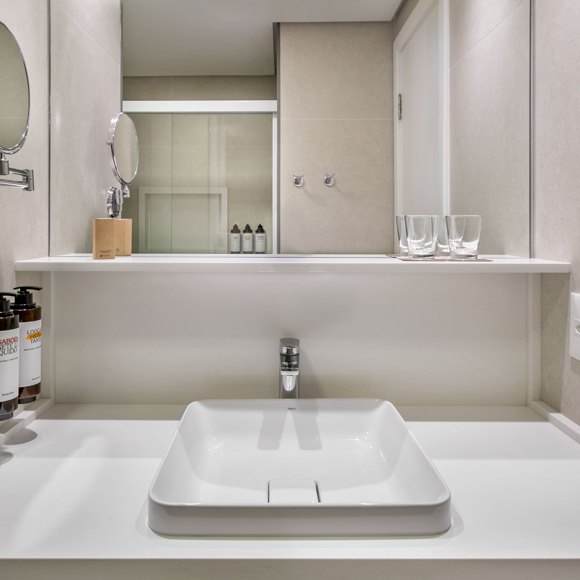 Modern hotel bathroom vanity with square sink, chrome faucet, and mirror.