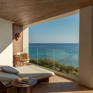 a lounge chair and a table overlooking the ocean