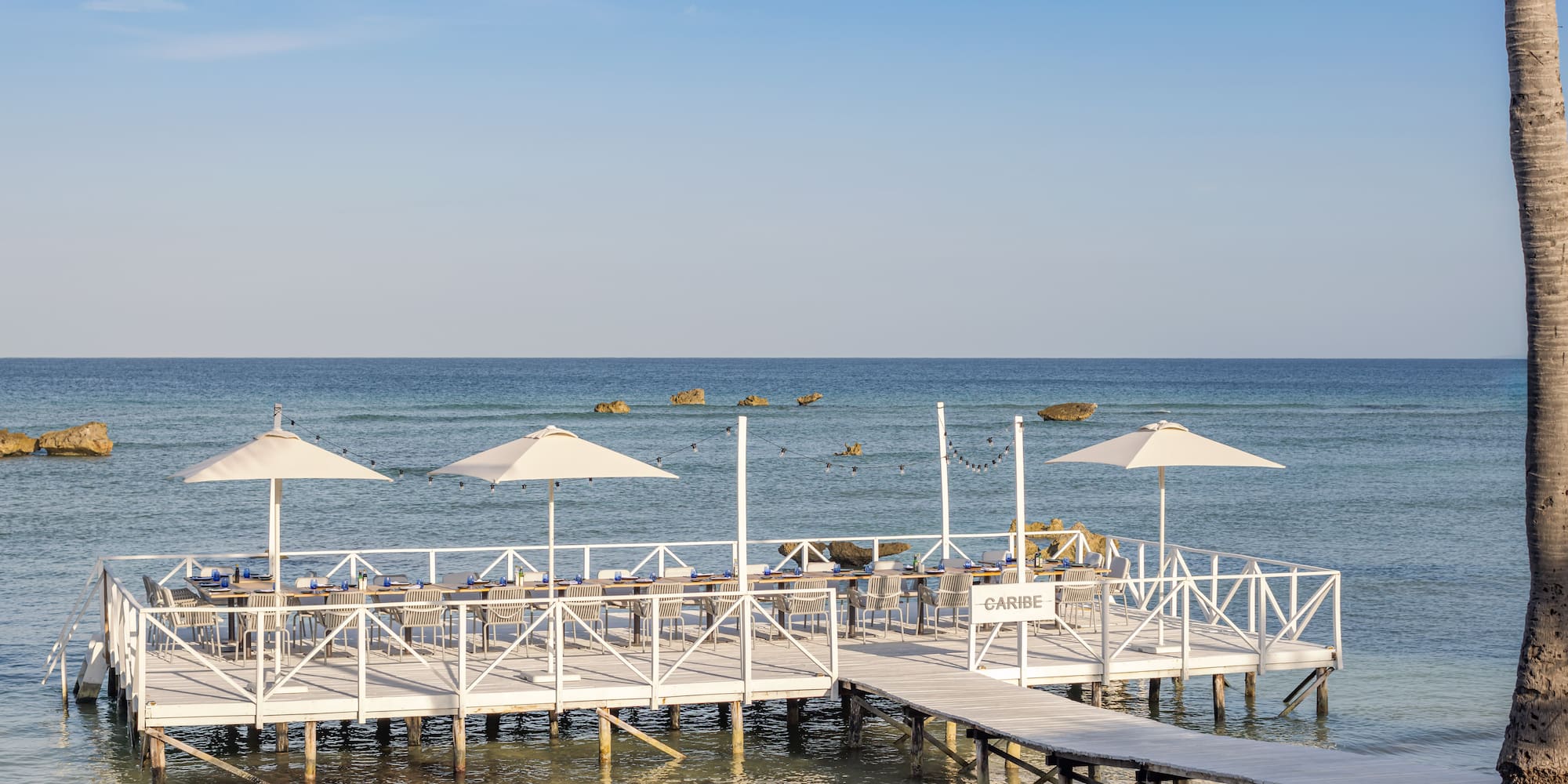 a white dock with umbrellas on the water