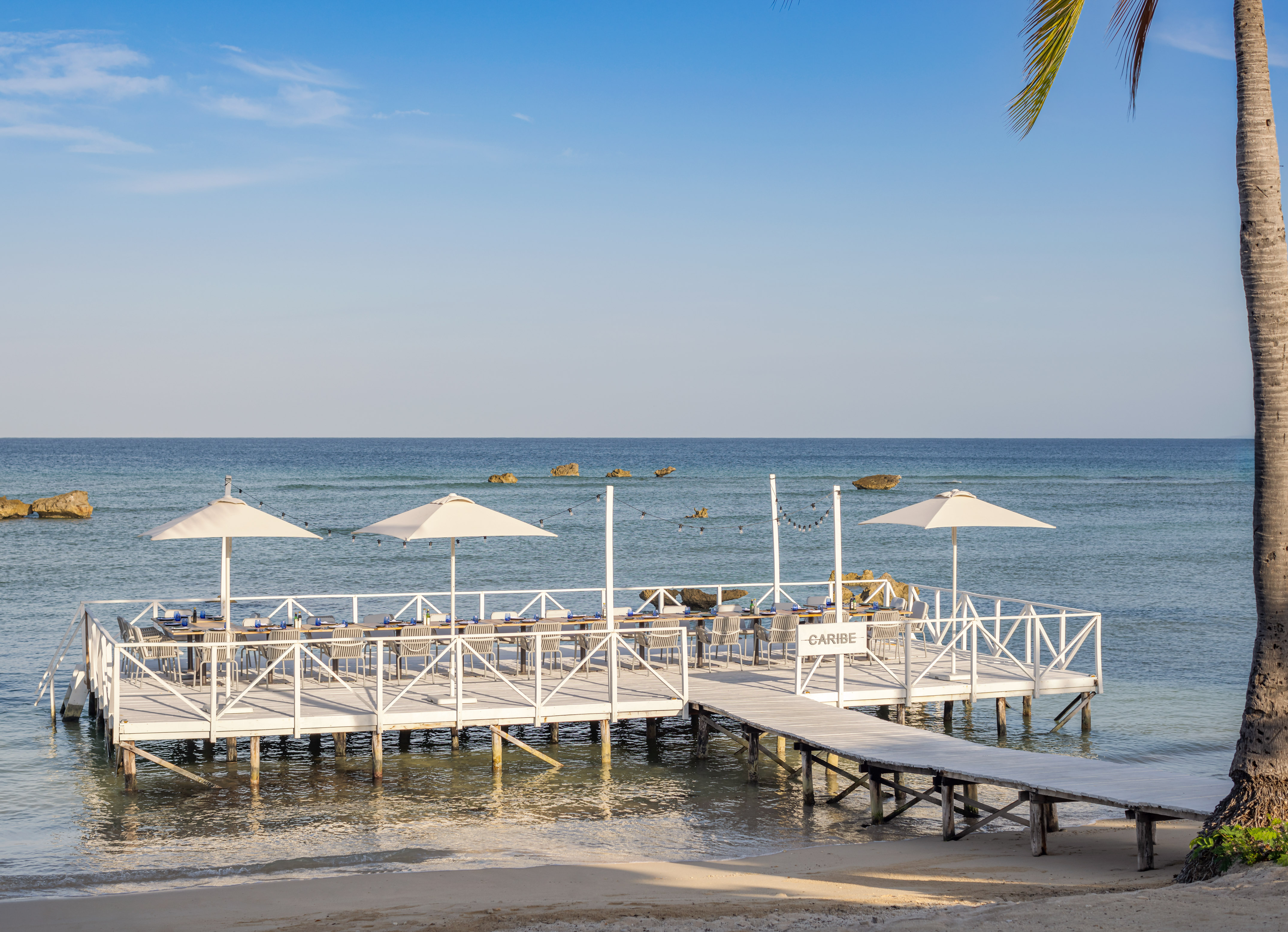 a white dock with umbrellas on the water