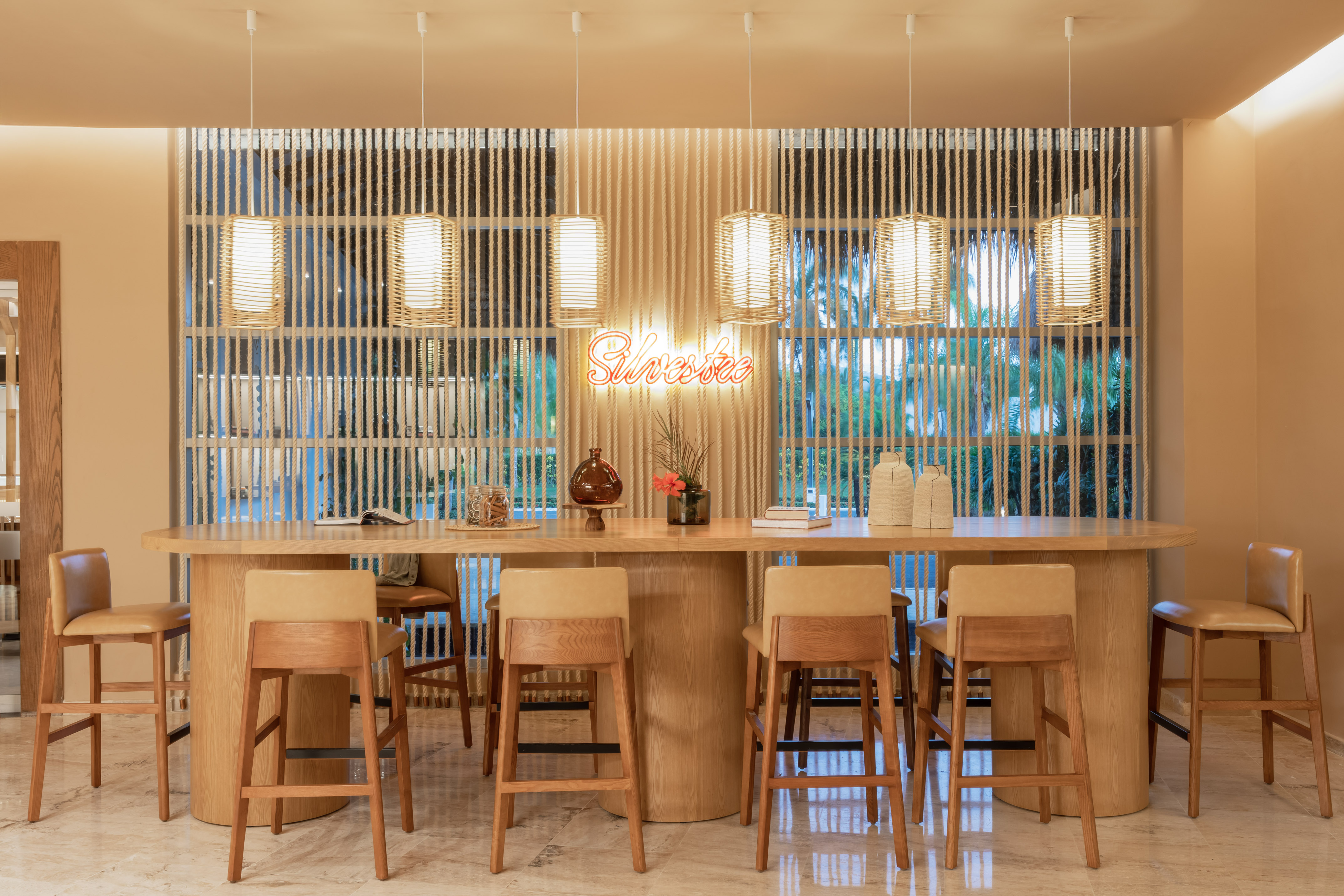 Modern wooden bar, bar stools, wicker lights, and vibrant neon sign.